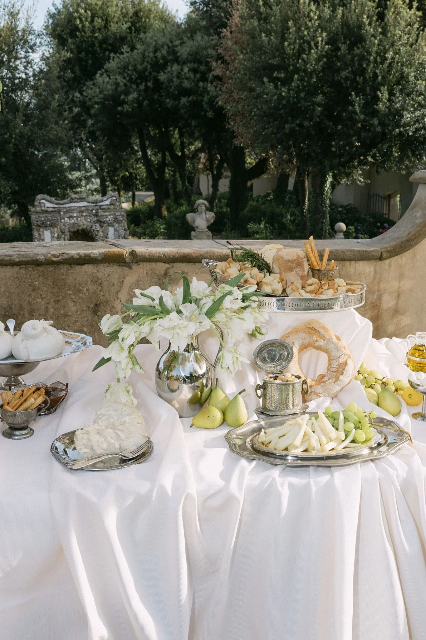 Wedding buffet with draped tablecloth, silver trays, bread and cheeses