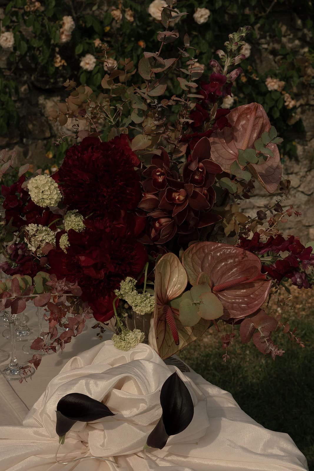 Elegant floral styling in burgundy, white, green, and soft pink tones for wedding buffet flower composition