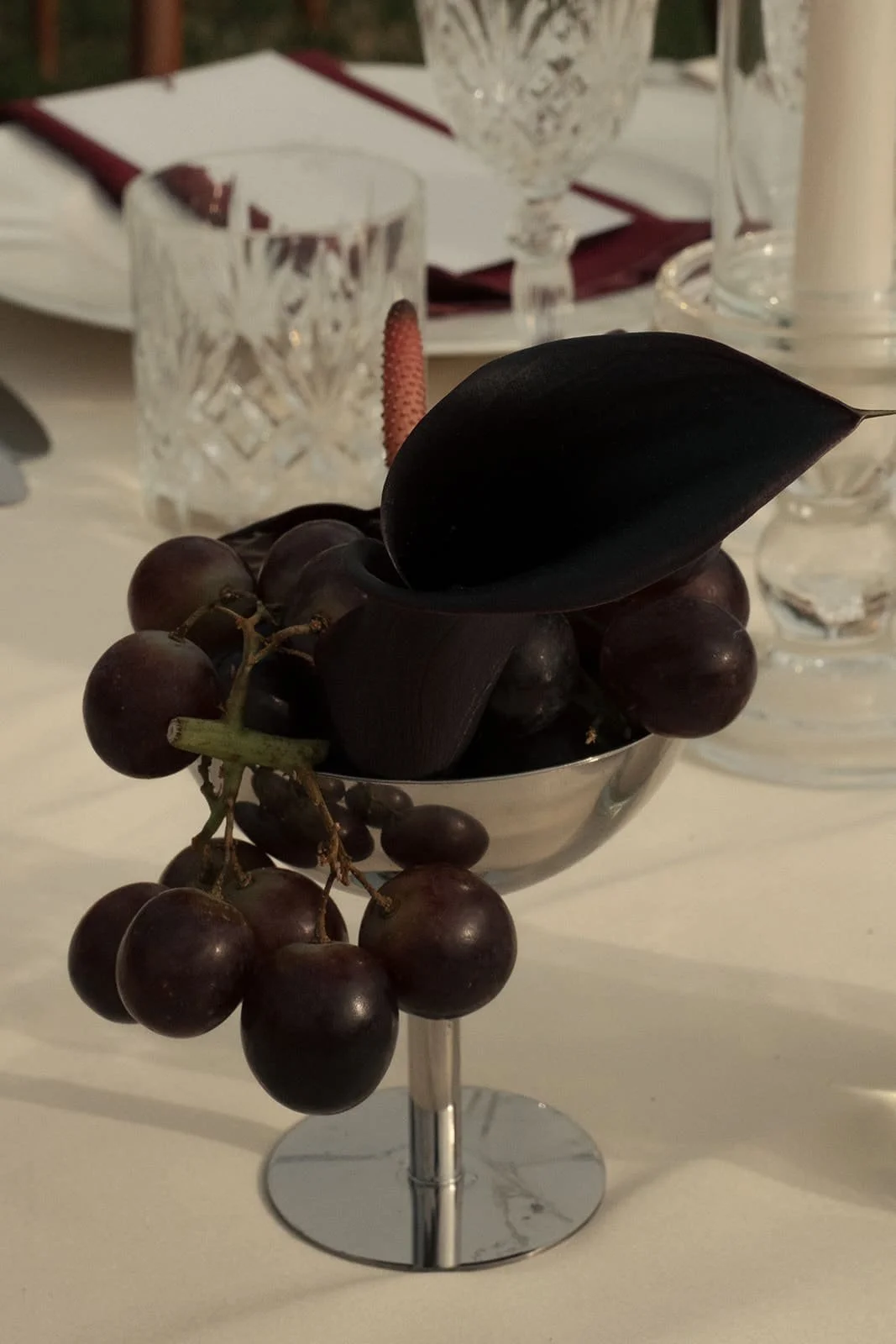 Silver cup with burgundy grapes and flower as wedding table decor