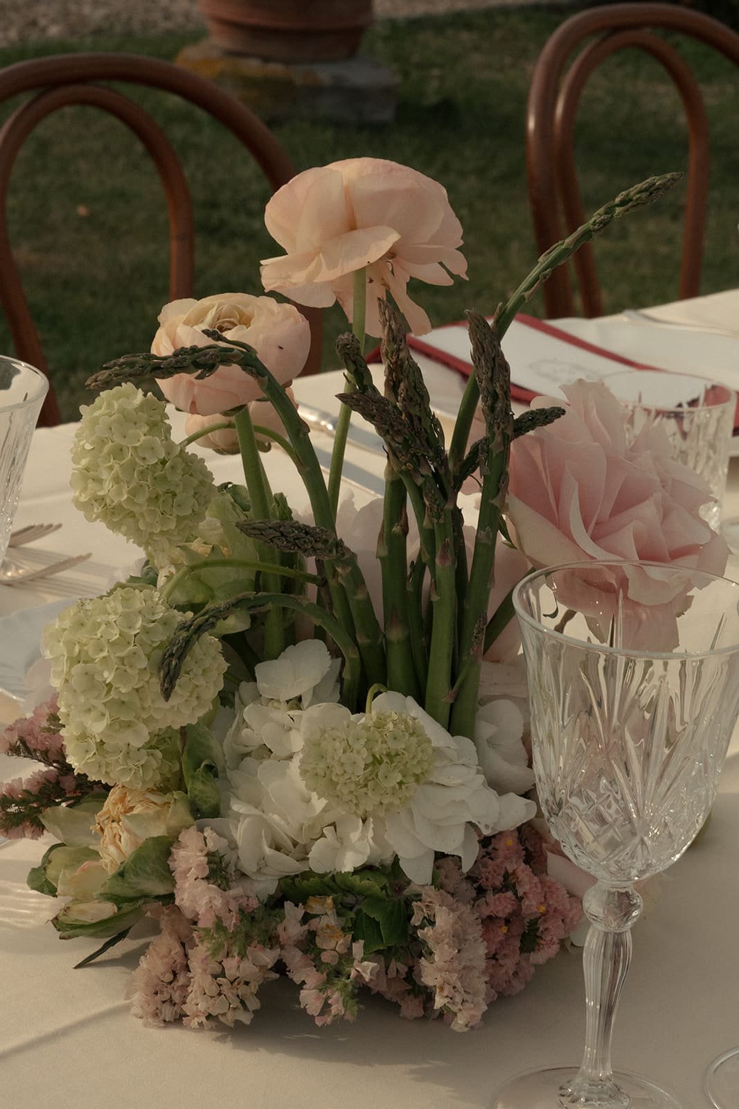 Wedding table centerpiece with pink, green and white flowers and vegetables as asparagus
