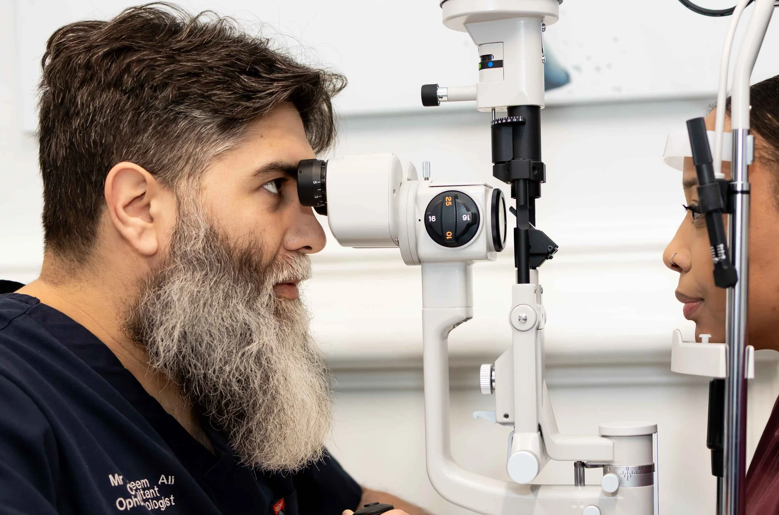 An optometrist performing eye examination on a female patient using a slit lamp in an eye clinic.