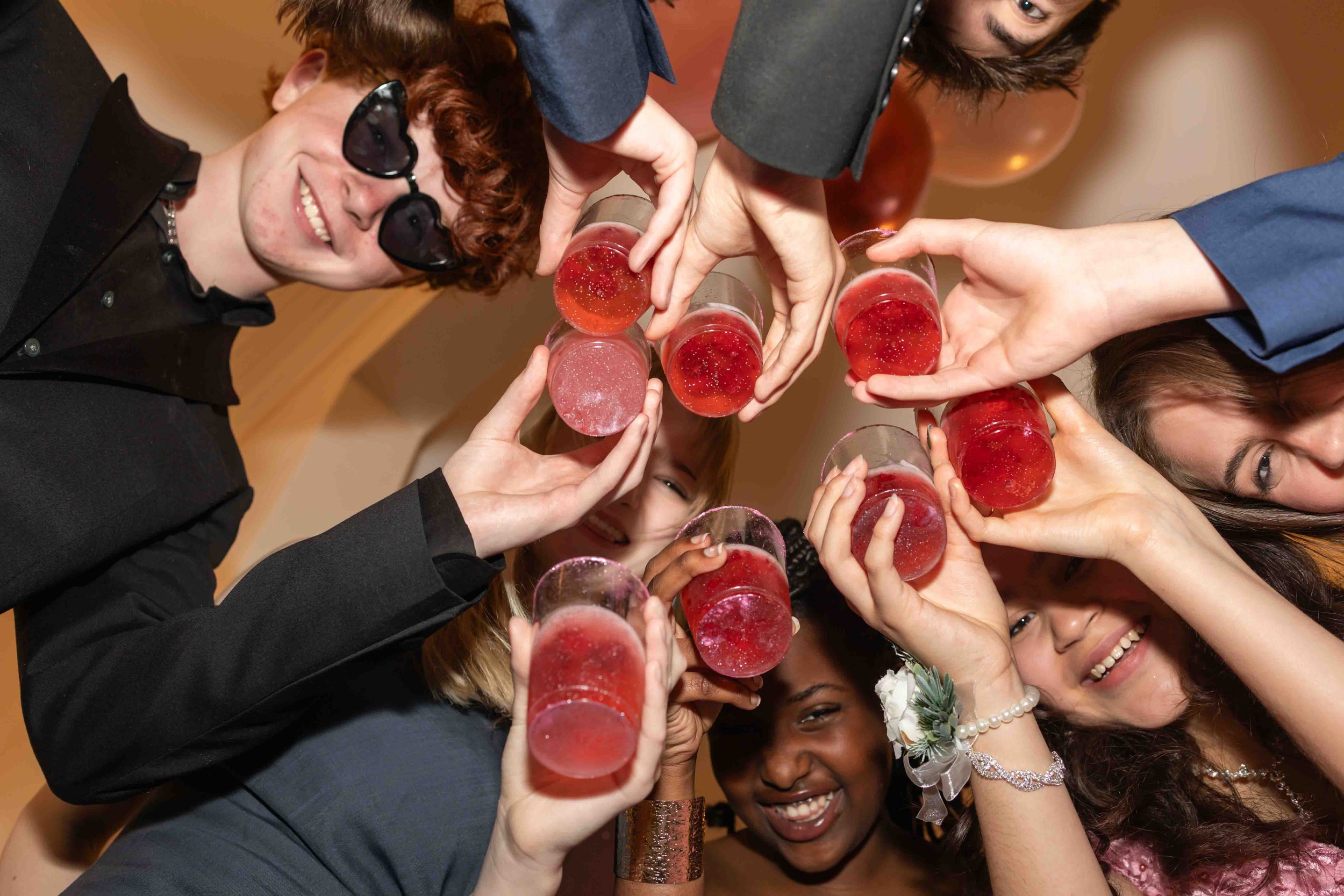 Group of diverse friends celebrating toasting with pink drinks at a party.