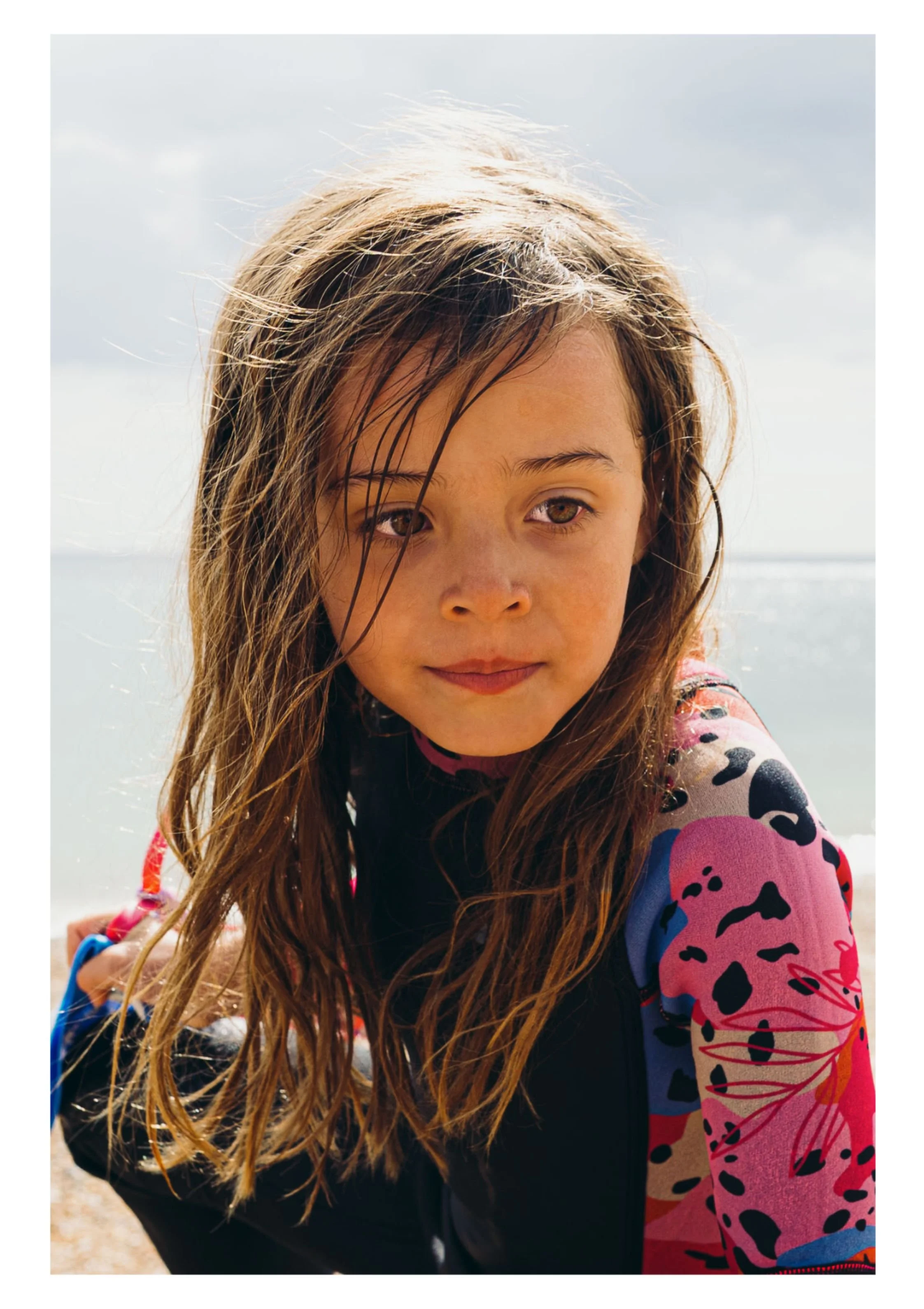 Hove family photoshoot, an unposed portrait of her daughter in wetsuit at the beach. Natural, lifestyle family photography in Hove, Brighton and across Sussex.