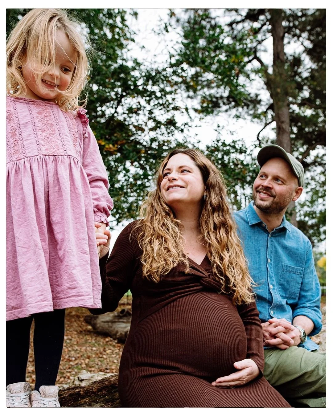 Natural maternity photo session in Regent's Park, central London. Mother, pregnant with second child holding daughter's hands.