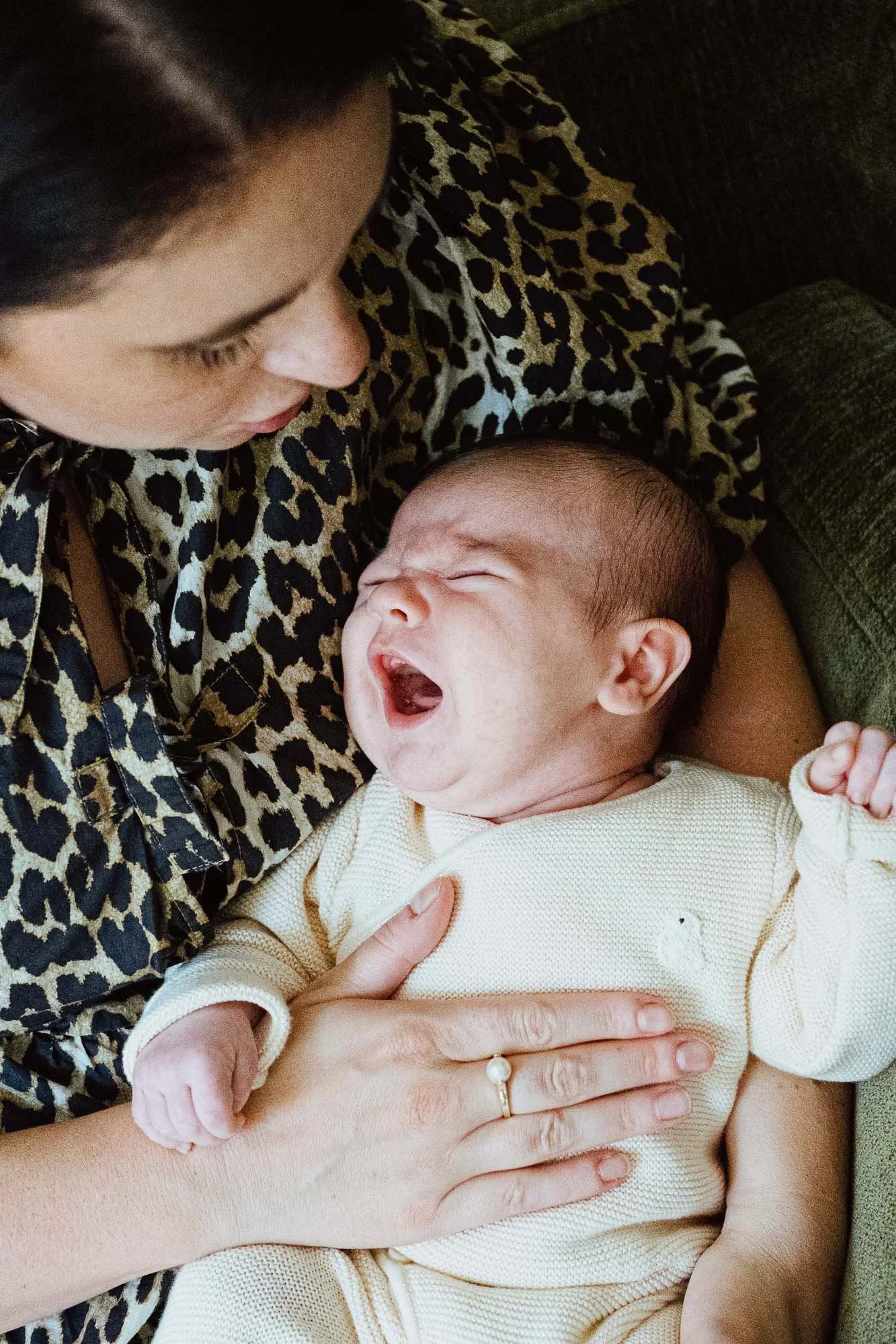In home newborn photography in Wandsworth, South London. Baby boy yawning on mother's lap.