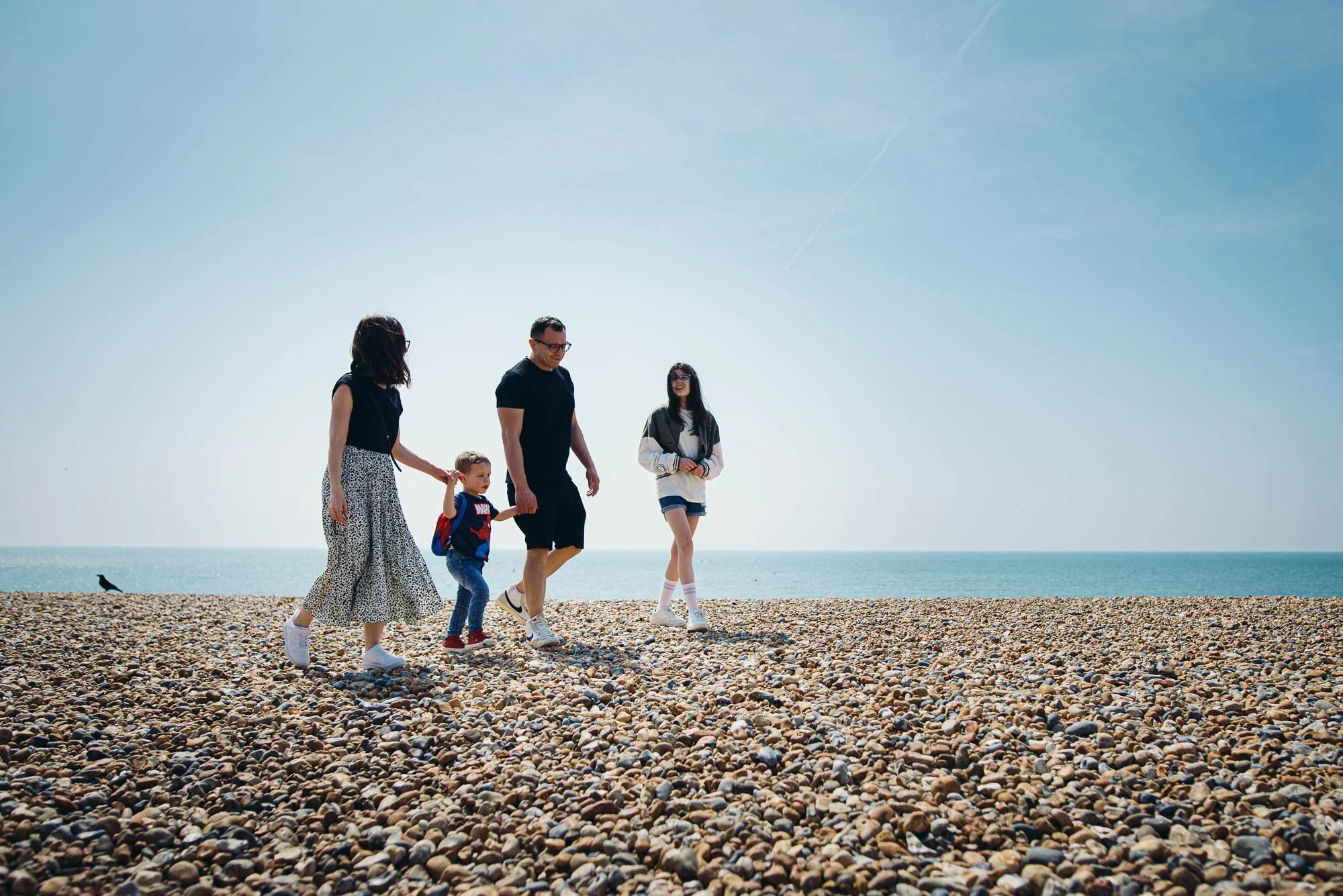 family-photoshoot-brighton-hove-beach-pebbles-blue-sky-summer-beach-photography-sussex-family-walking-on-beach.jpg