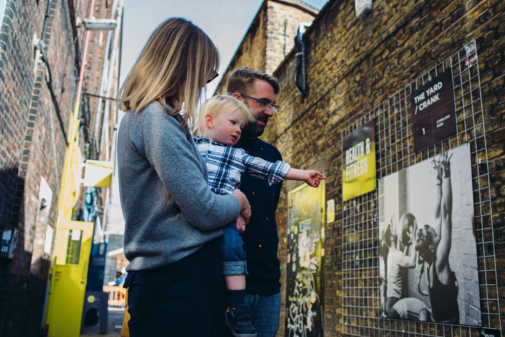 peckham-bussey-building-family-photoshoot-documentary-photography-dad-mum-little-boy-pointing-at-wall.jpg