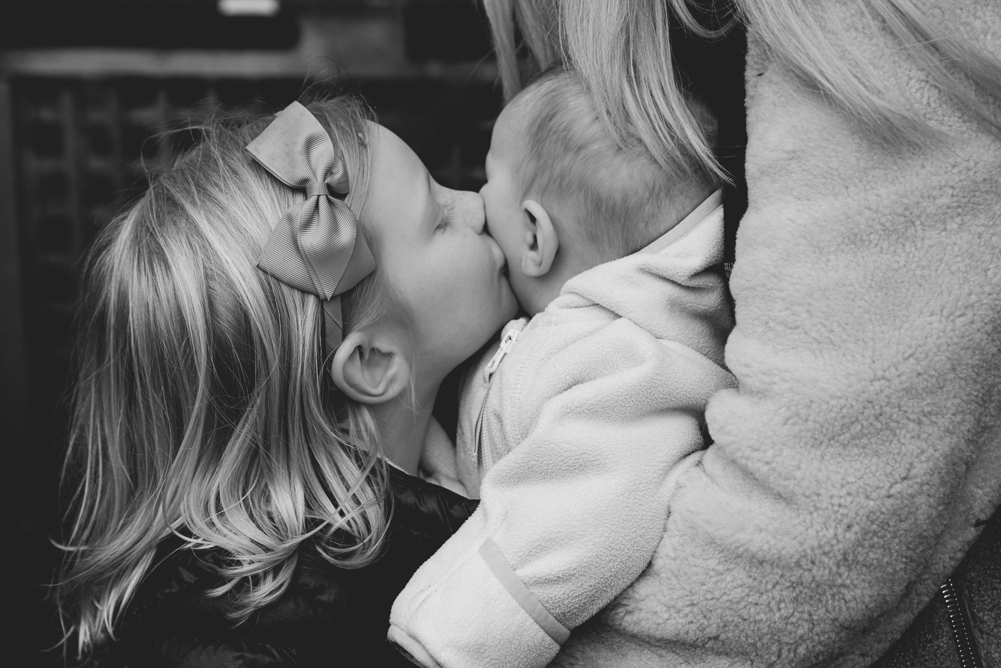 london-family-photographer-sister-kissing-baby-newborn-girl-family-photoshoot-belgravia.jpg