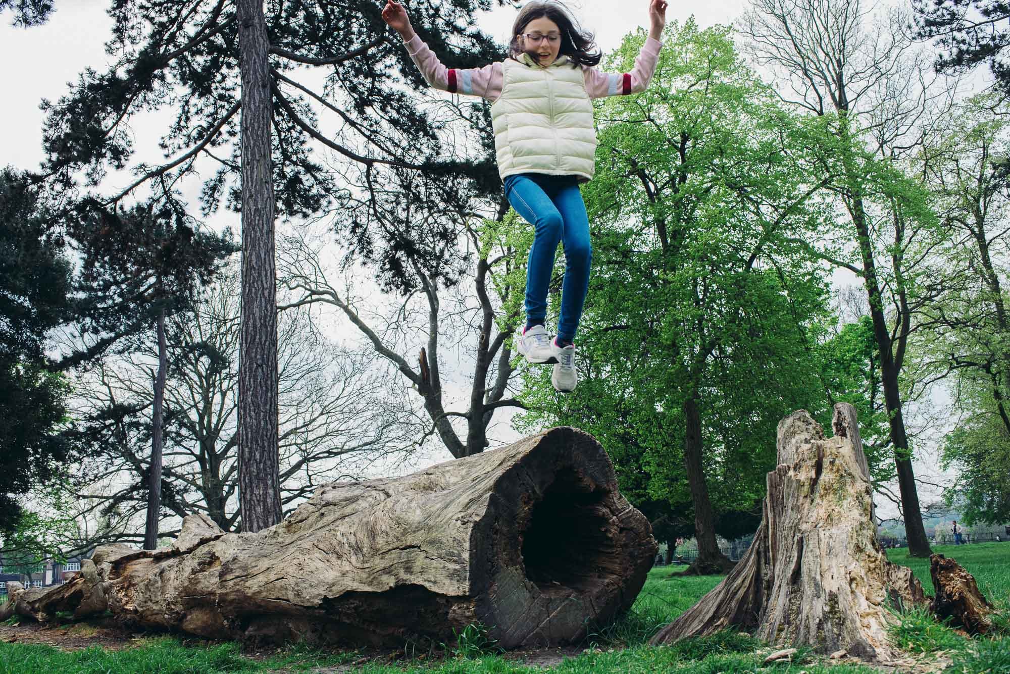 girl-jumping-off-log-peckham-rye-park-london-family-photographer-children-photography-documentary-style.jpg