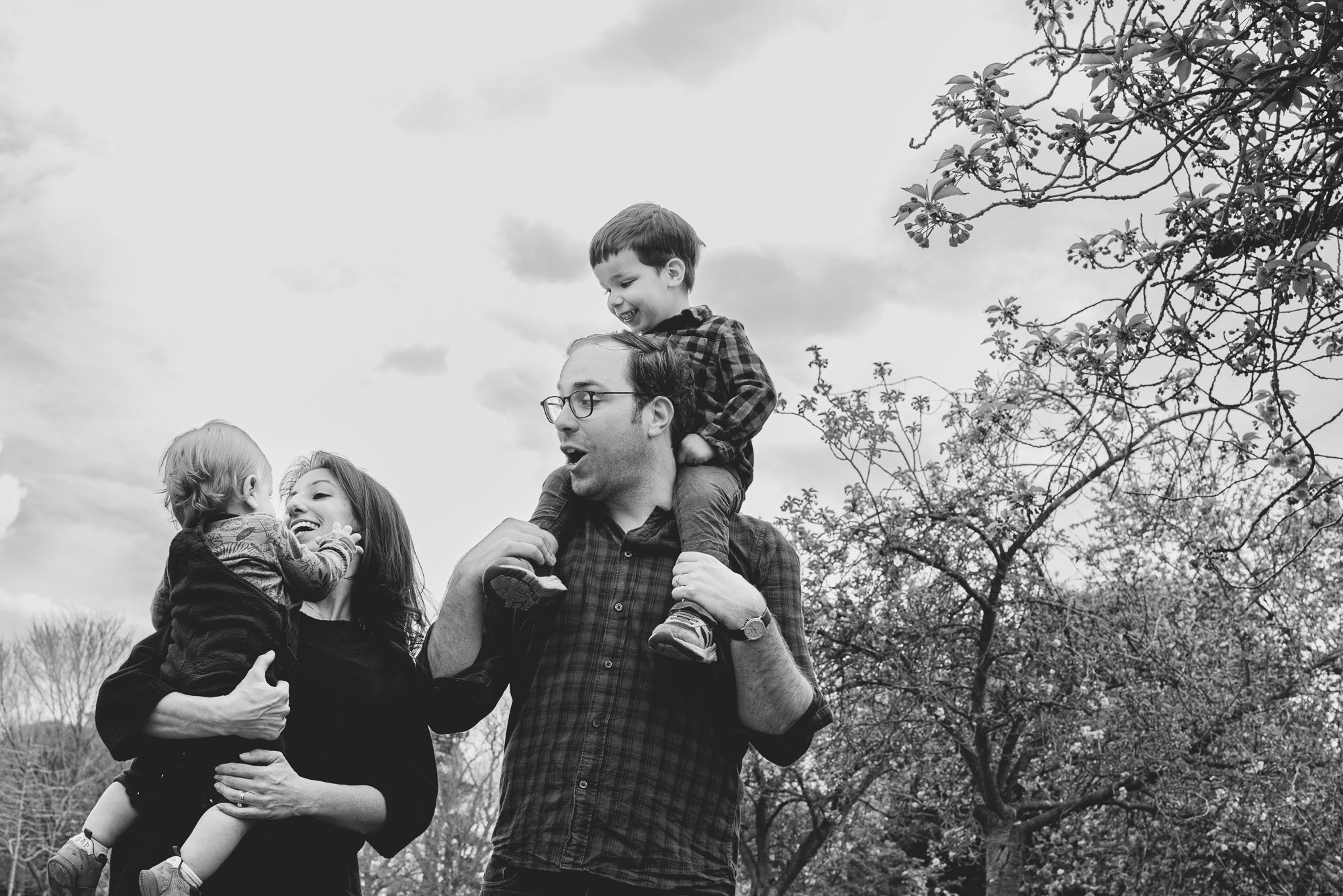 unposed-family-portrait-dulwich-parents-boys-on-shoulders-dad-park-black-and-white-family-photo-peckham-london.jpg