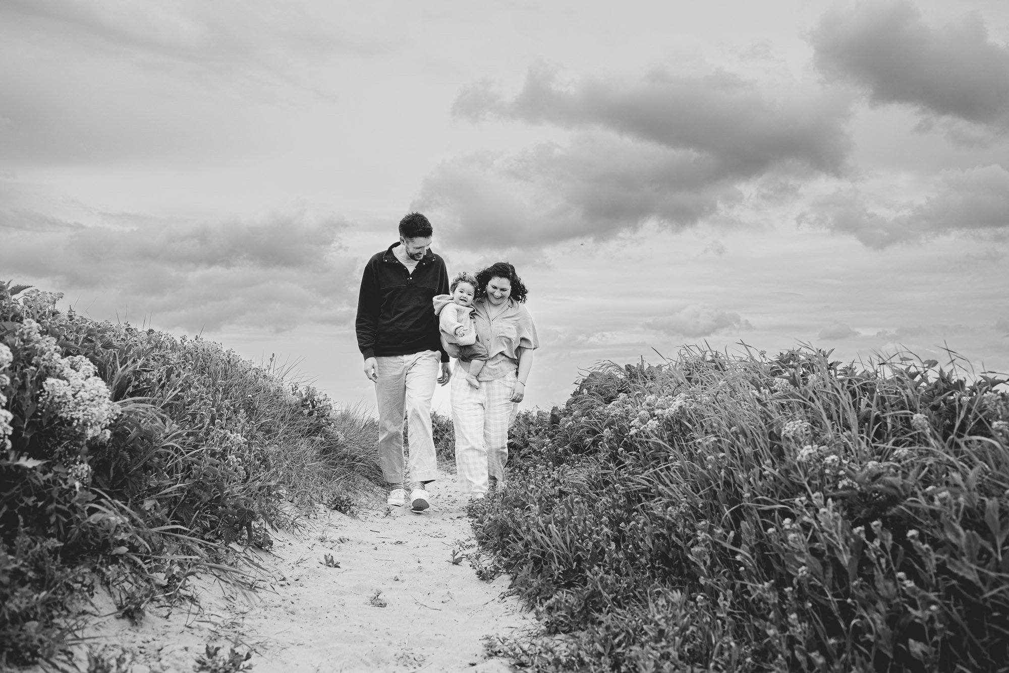 nautral-family-portrait-black-and-white-beach-west-wittering-clouds-walking-towards-camera.jpg