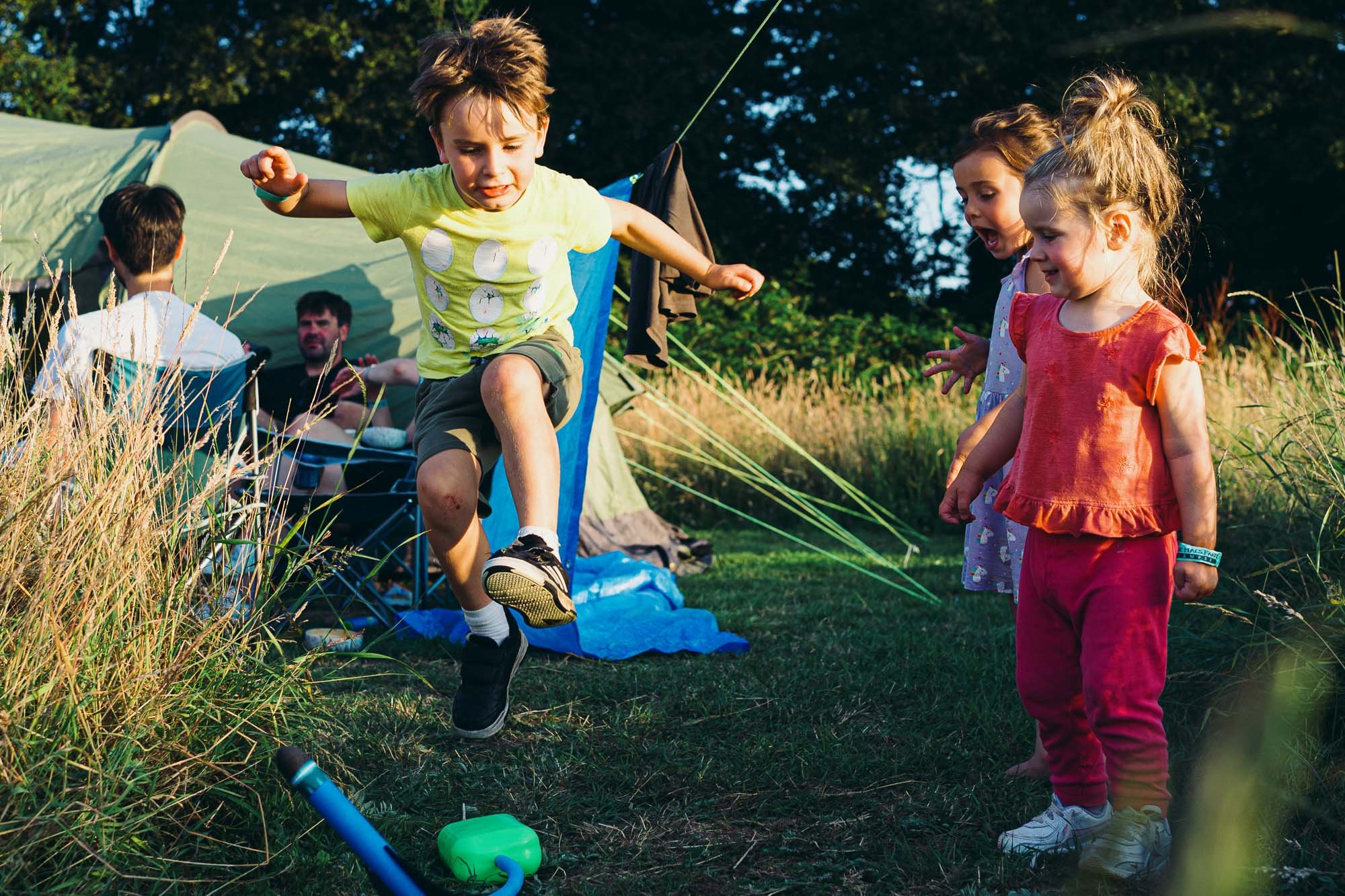boy-jumping-rocket-launcher-girls-watching-unposed-family-photography-sussex-ditchling-campsite.jpg