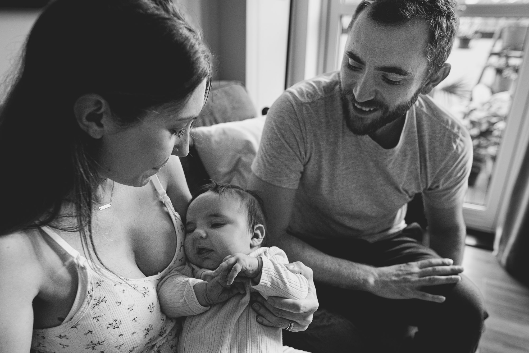 unposed-newborn-photographer-london-family-on-sofa-during-newborn-photoshoot-at-home-london-black-and-white-portrait.jpg