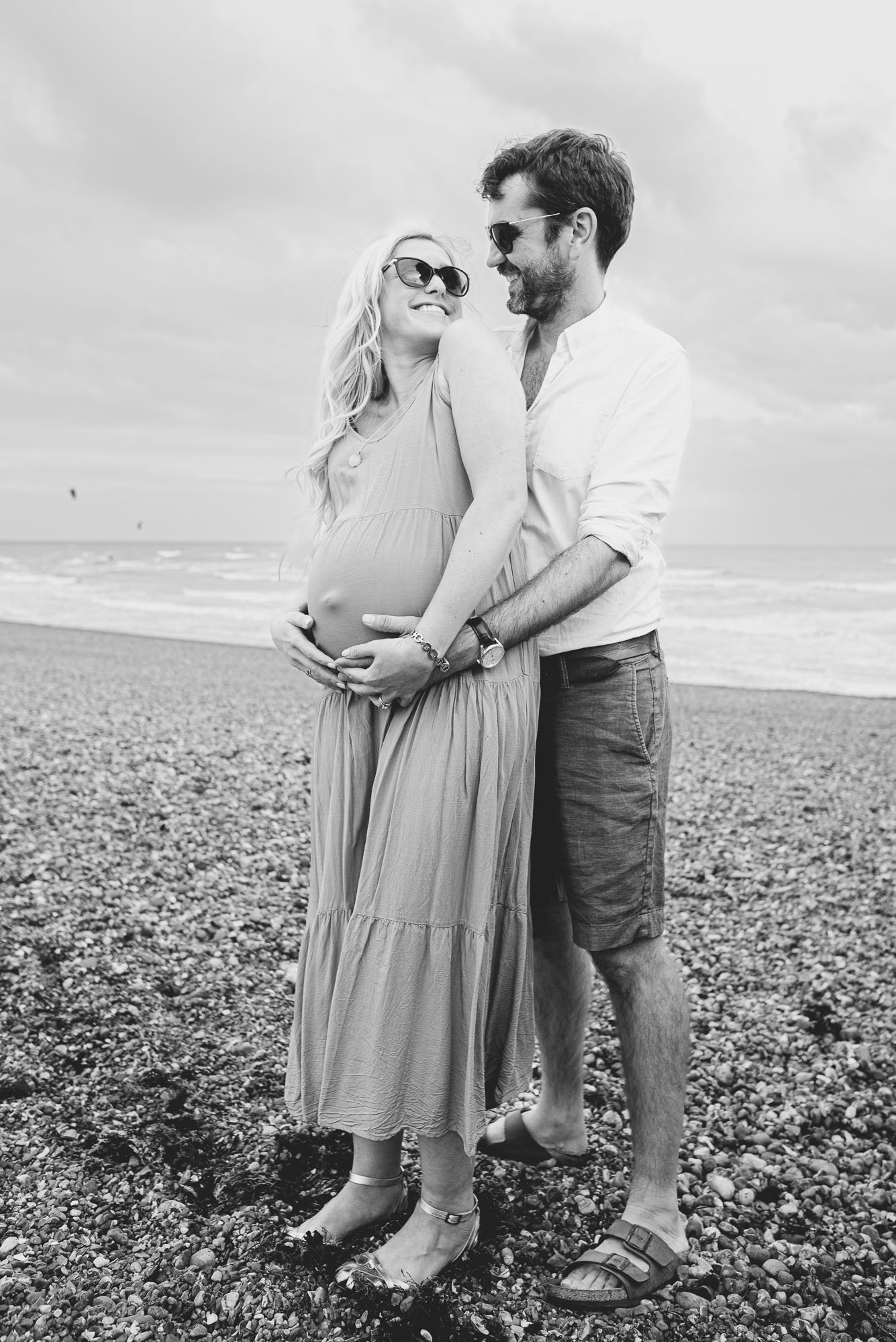 maternity-beach-photoshoot-hove-brighton-couple-hugging-posing-hove-beach-sussex-matenrity-photography-black-and-white-portrait.jpg