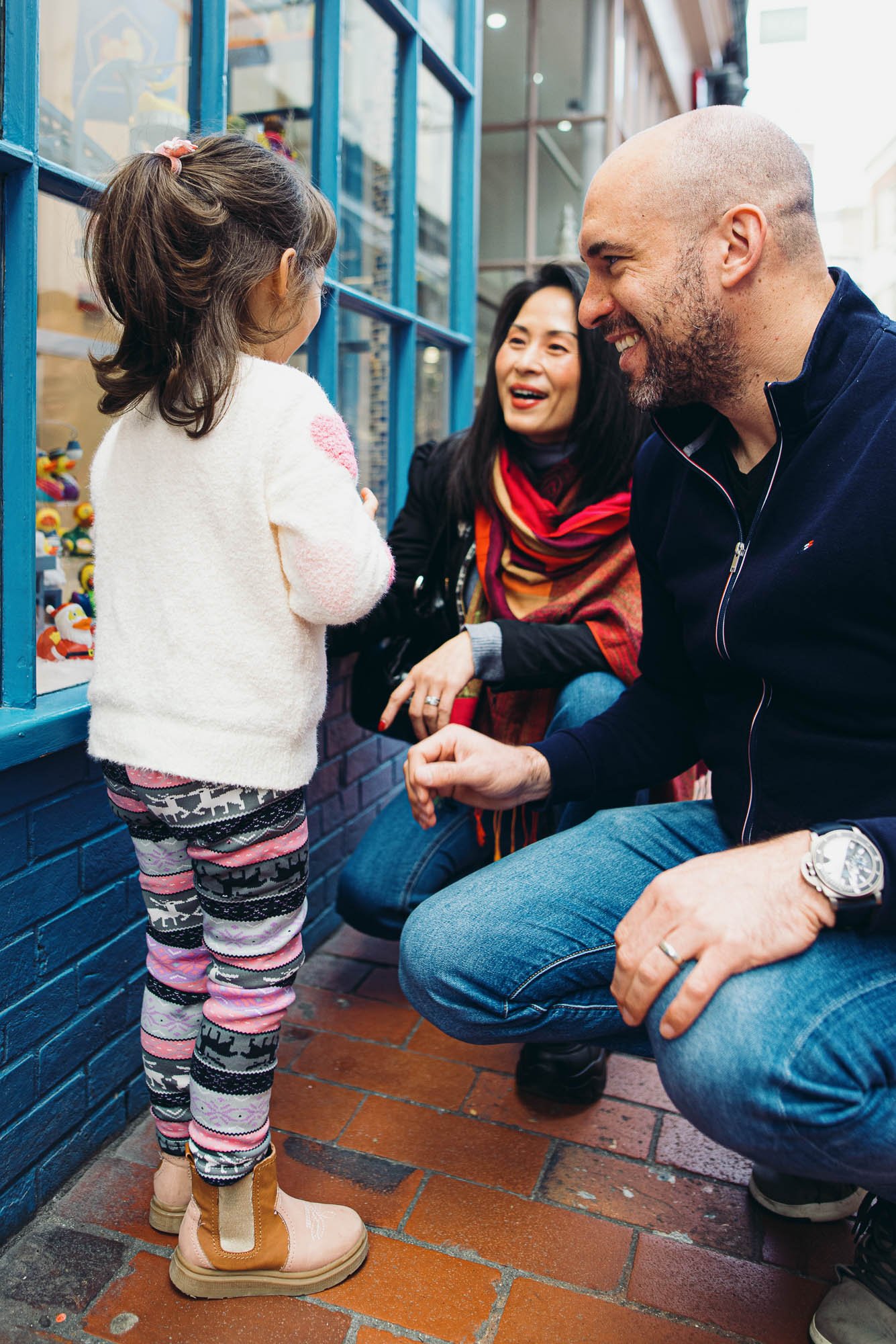 girl-parents-smiling-outdoor-family-photoshoot-brighton-lanes-hove-lewes-worthing-eastbourne-unposed-family-photos.jpg