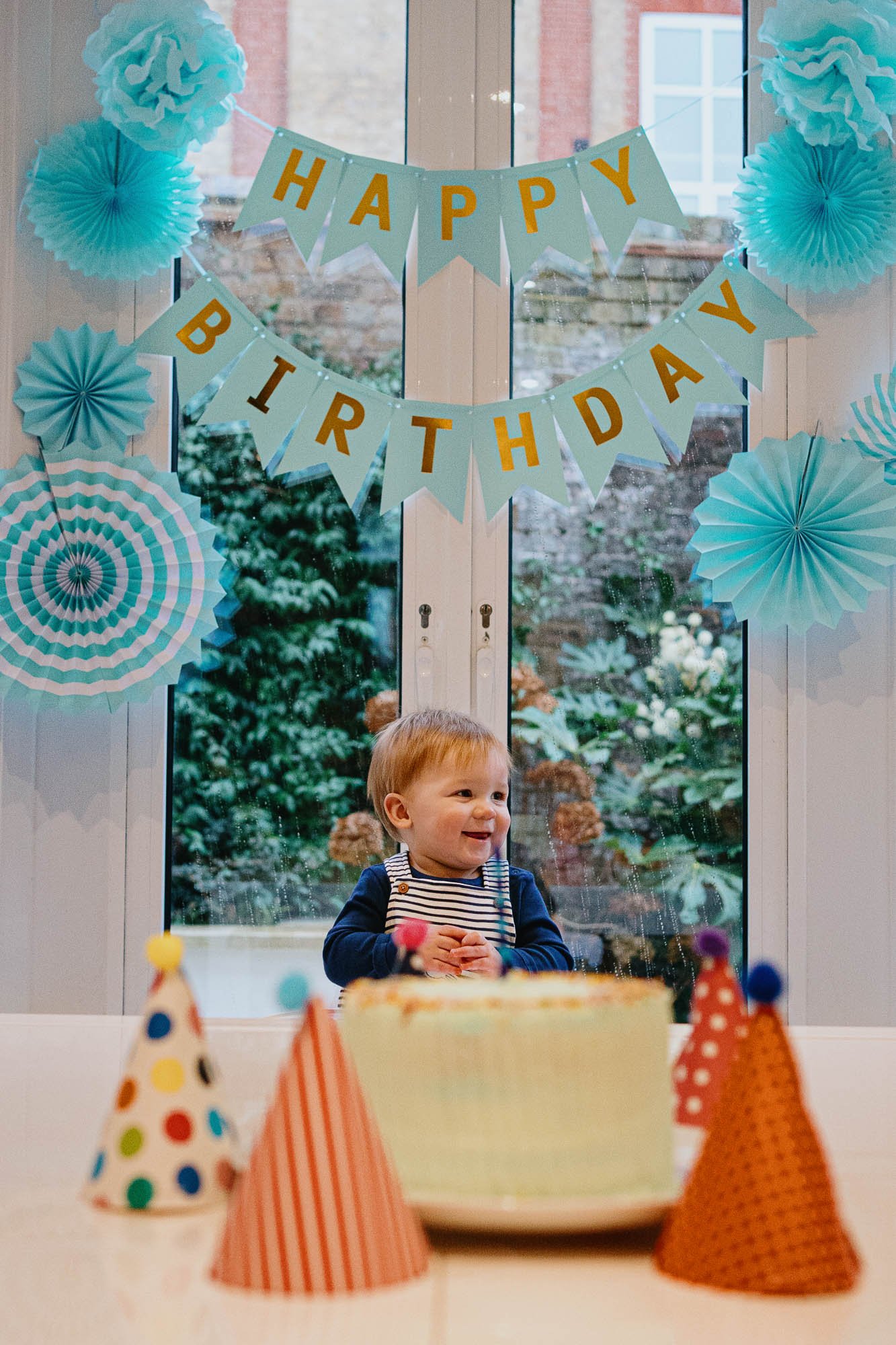 first-birthday-photographer-children-part-at-home-london-brighton-hove-sussex-natural-unposed-family-photography-boy-and-birthday-cake-party-hats-bunting.jpg
