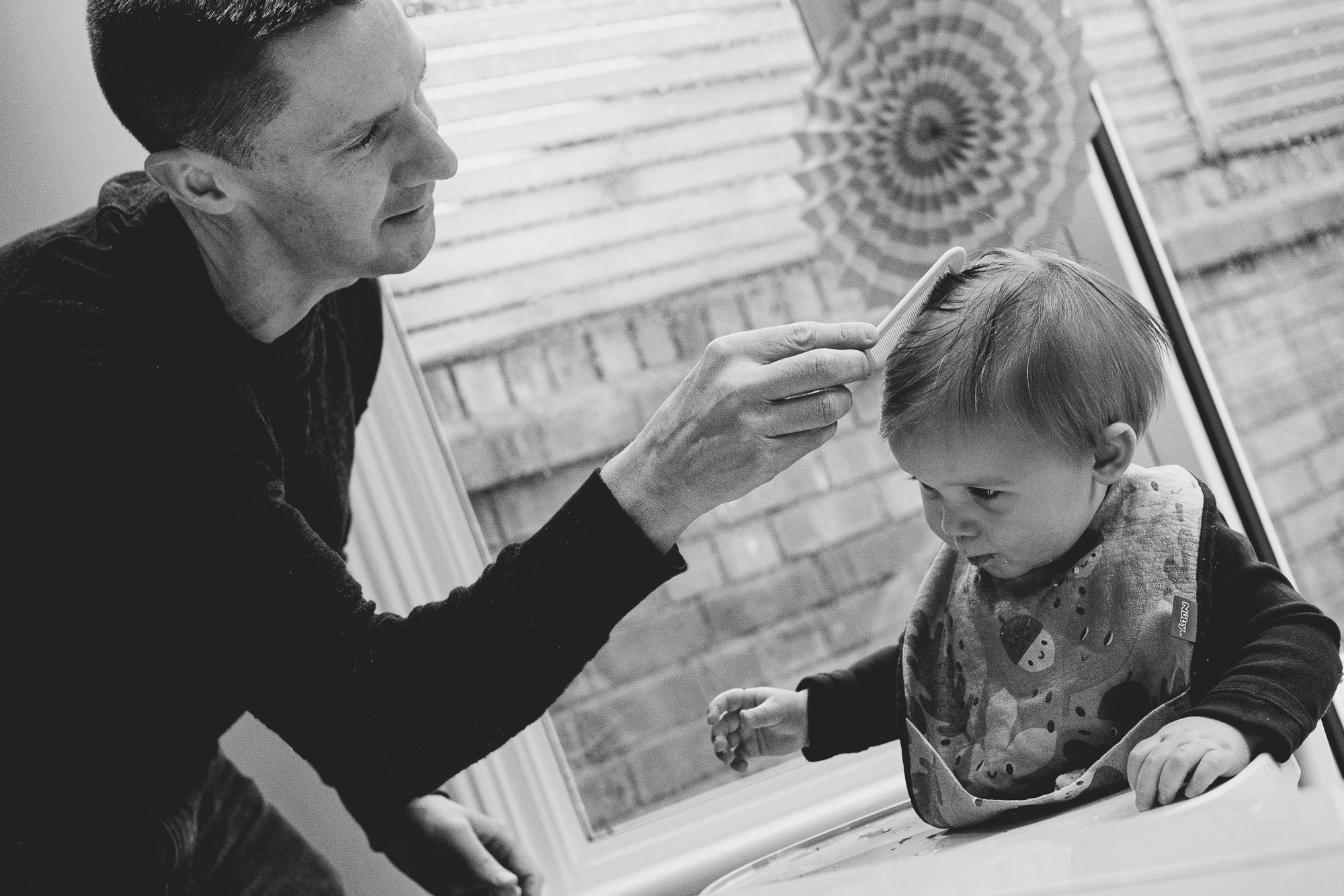 dad-combing-toddlers-hair-family-documentary-photographer-capturing-first-birthday-at-home-london-dulwich.jpg