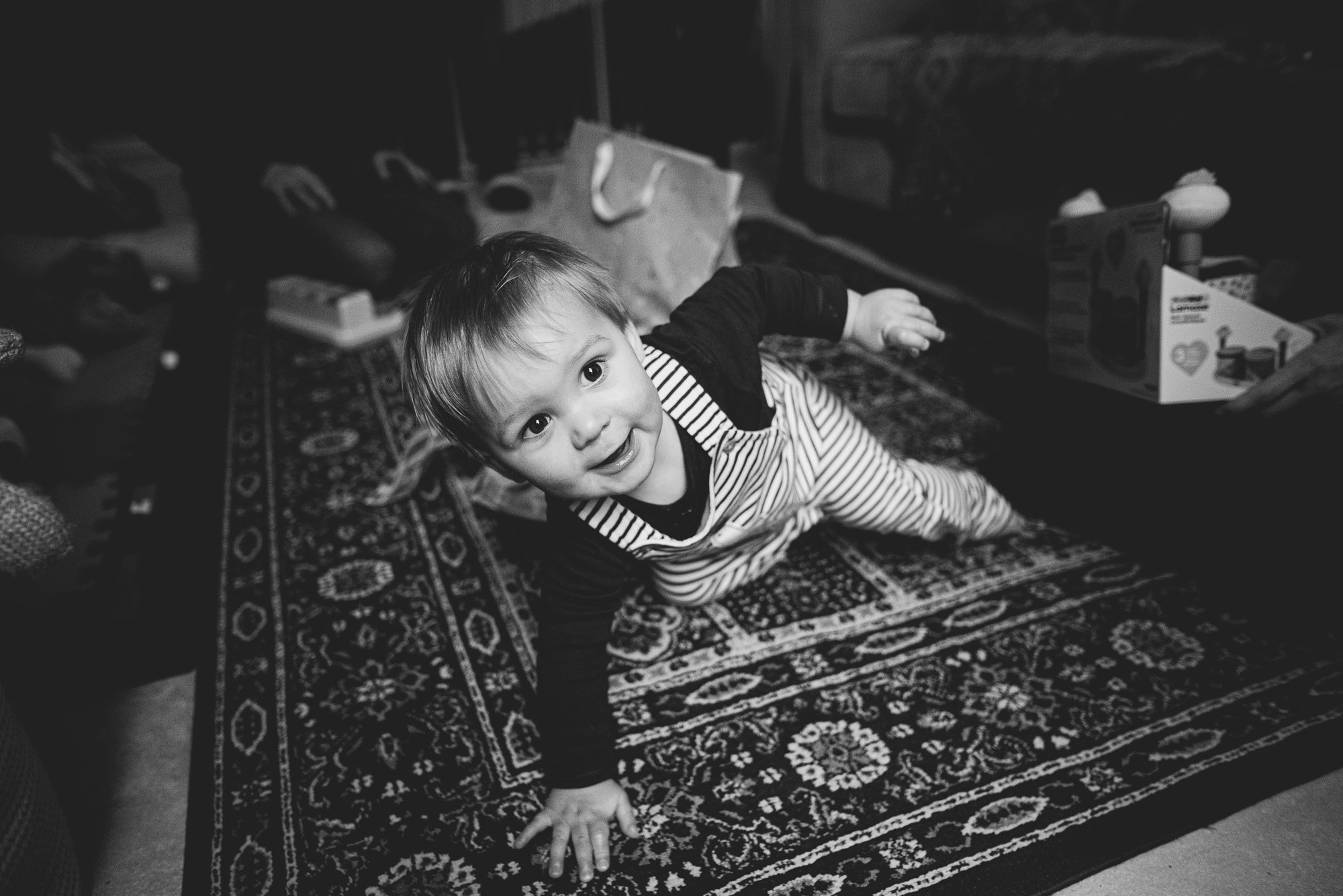 natural-family-photographer-london-unposed-birthday-boy-portrait-at-home-unwrapping-presents-black-and-white-portrait.jpg