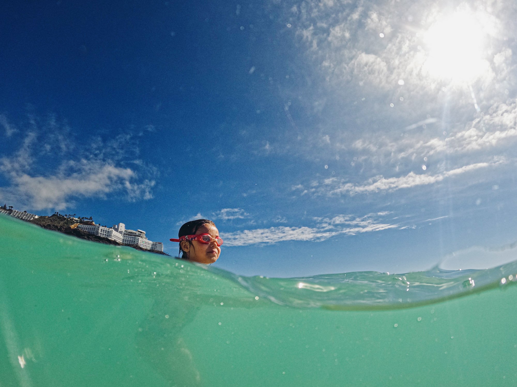 girl-goggles-in-sea-half-underwater-shot-beach-family-photographer-brighton-hove-sussex.jpg