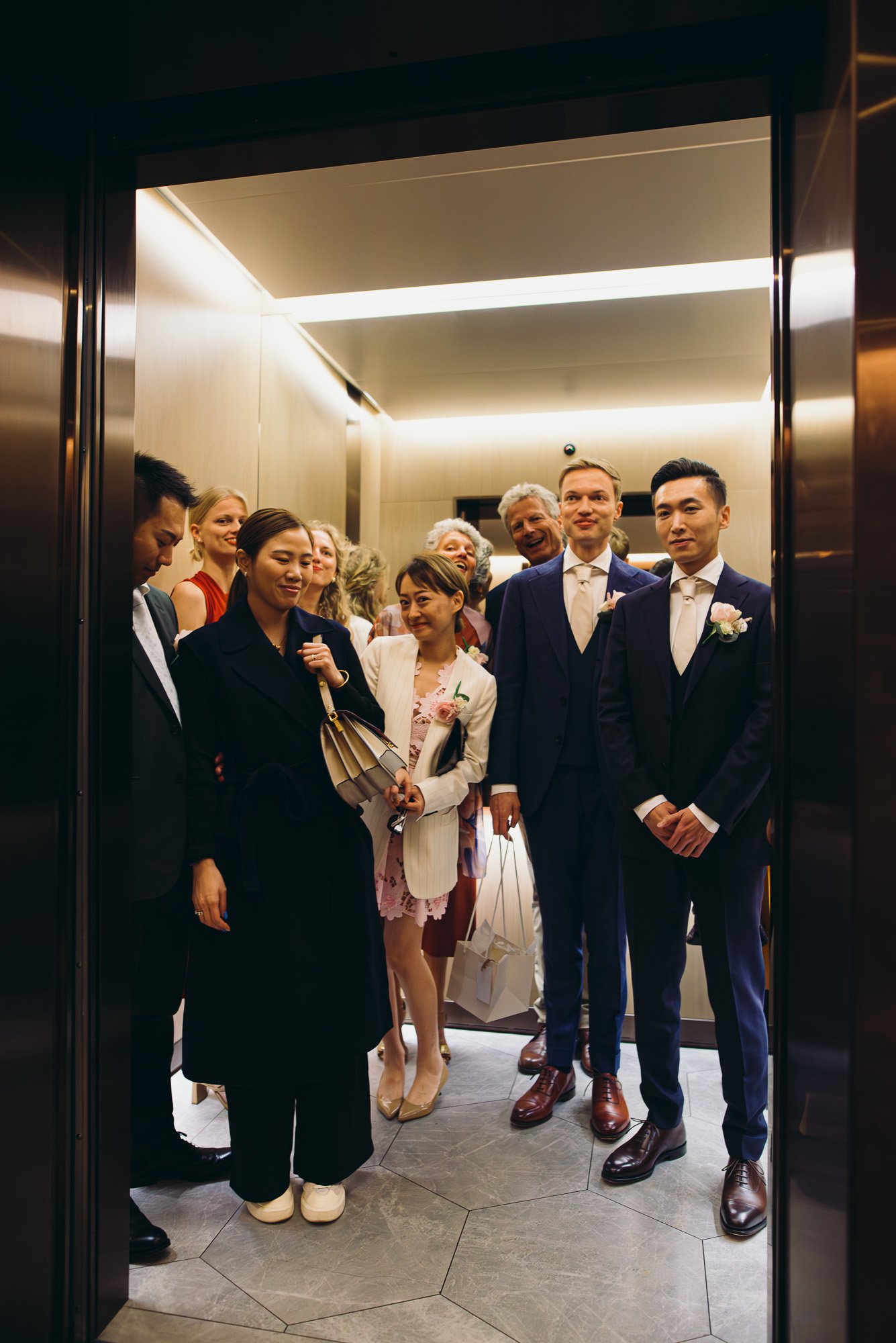 wedding-guests-in-lift-hotel-getting-ready-for-wedding-brighton-hove-wedding-photos-smiling-people.jpg