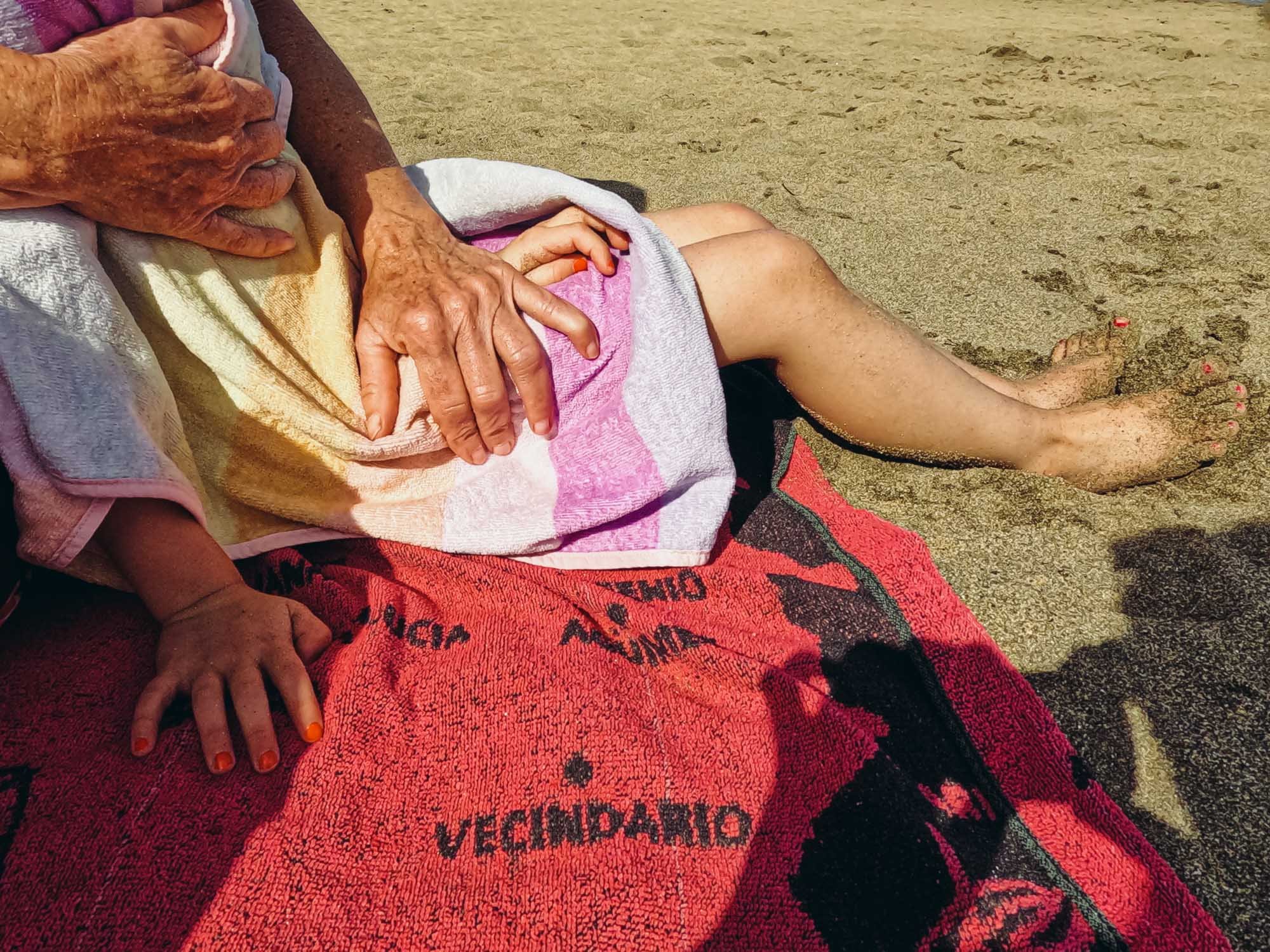 child-grandmother-sitting-beach-towel-holding-unposed-family-photography-real-family-life-sussex.jpg
