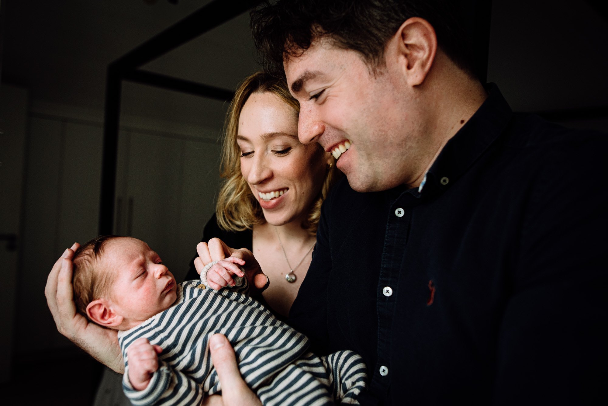 Award-winning natural newborn photographer in Greenwich photographing new parents with baby boy at home.