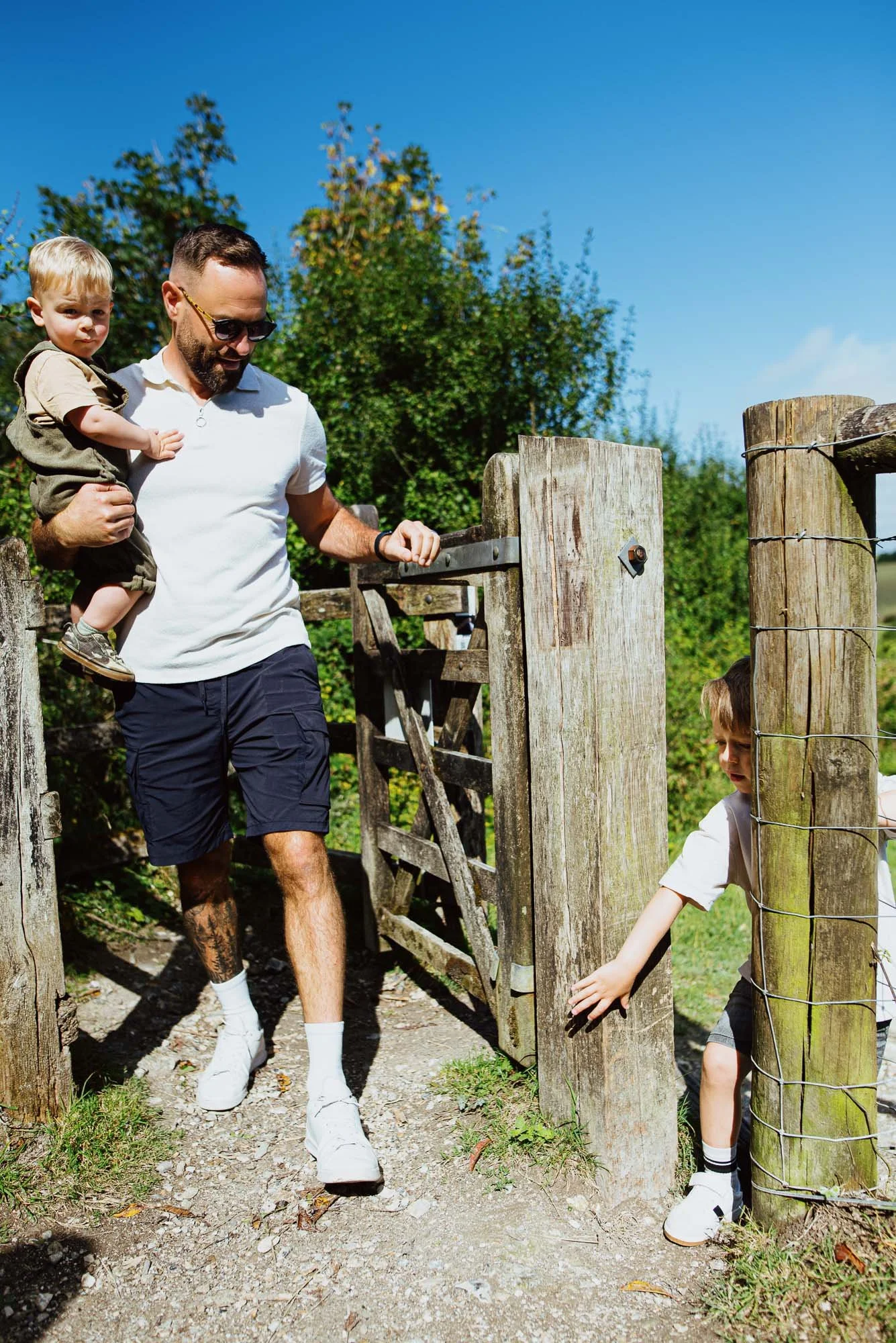Reigate Surrey Hills natural unposed family photography. Dad and his two sons opening a gate during their walk.