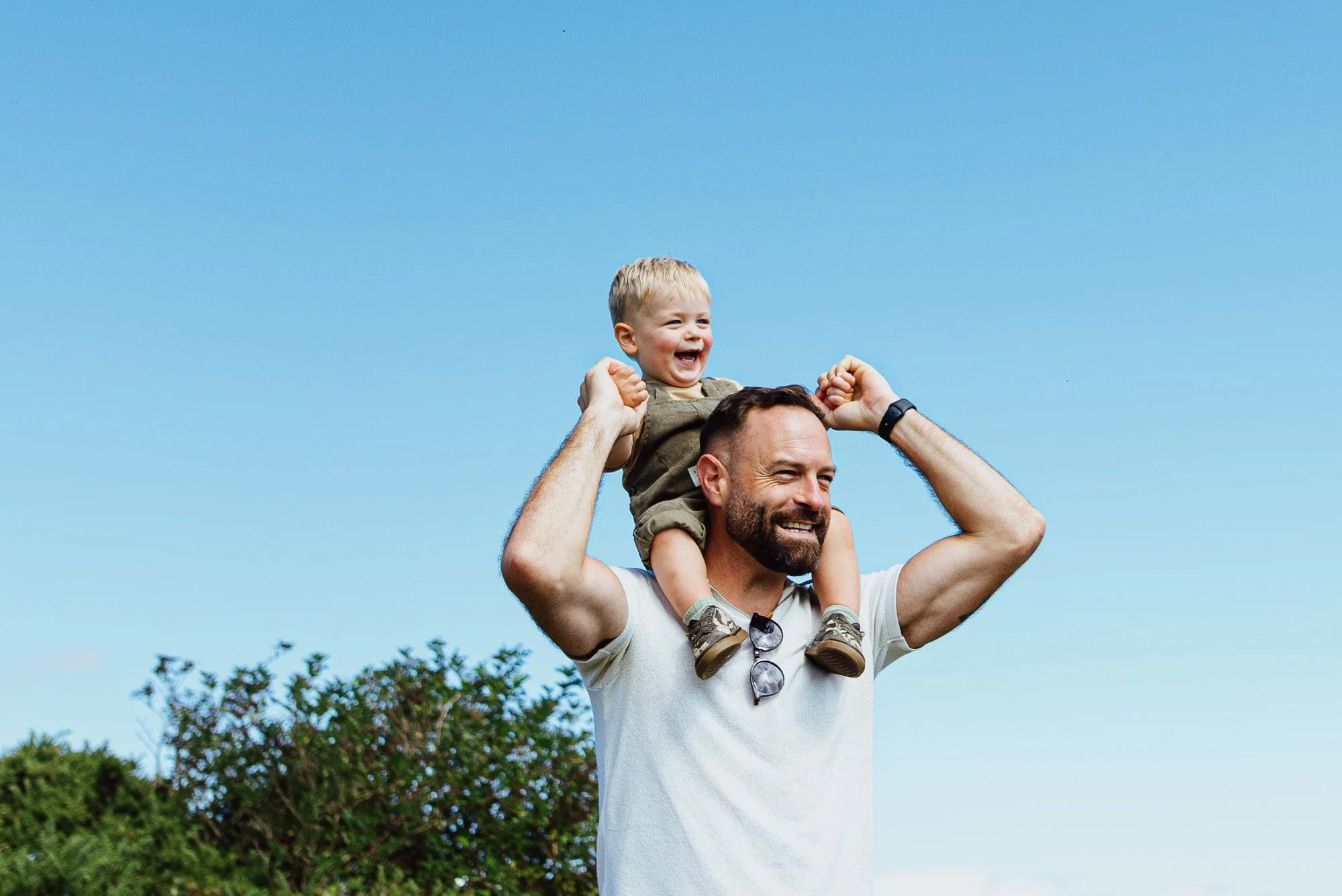 Lewes family photographer capturing dad with son on his shoulders walking he South Downs, Sussex. Natural family lifestyle photography in Lewes, Ditchling, Horsham and across Sussex.