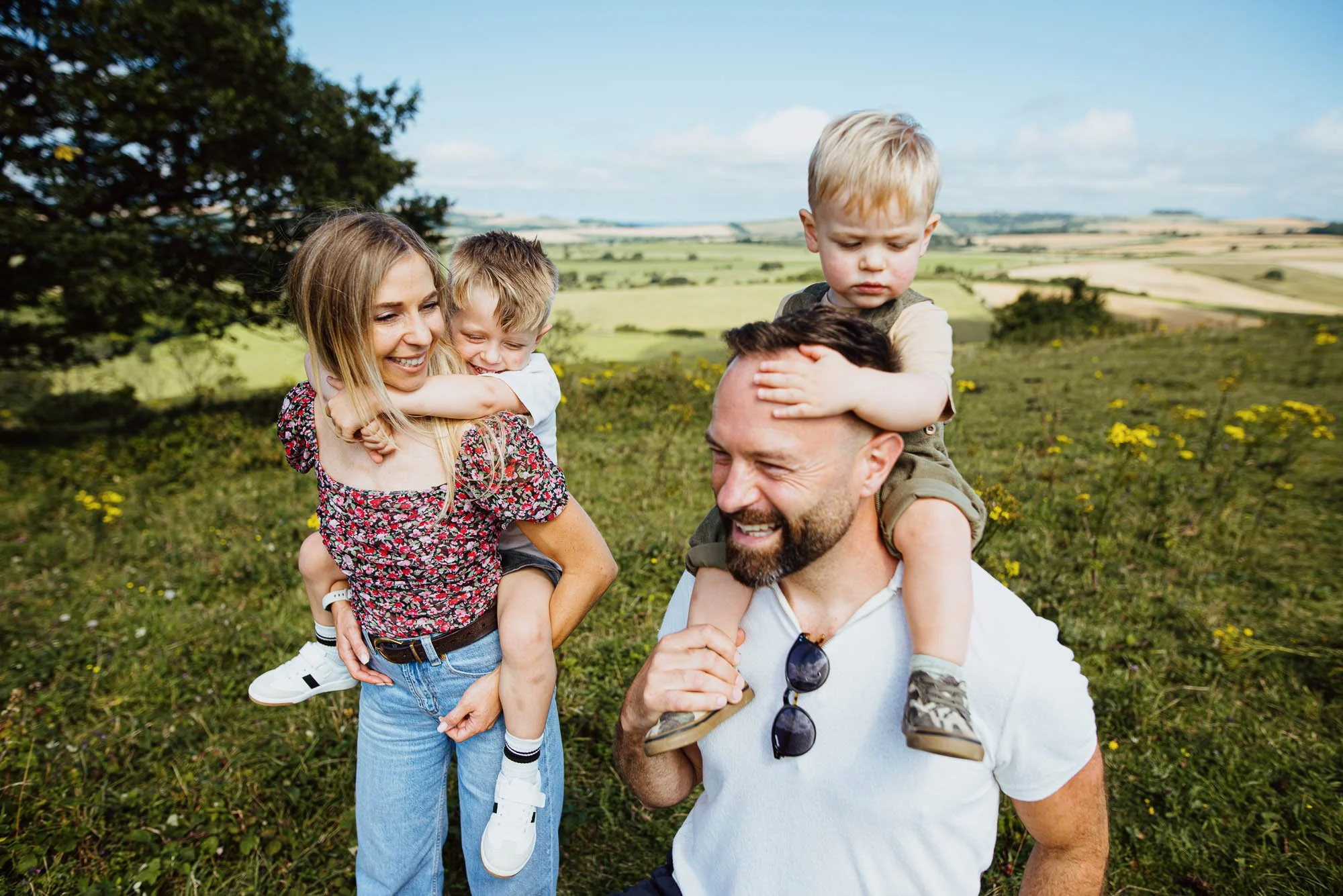 Hurstpierpoint family photoshoot outdoors in the South Downs. Portrait of parents and their two boys on top of the hill.