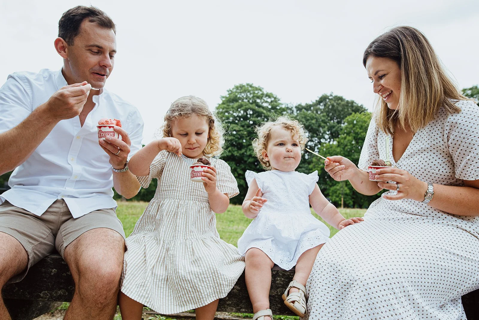 Fulham family photographer capturing family eating ice cream on Eel Brook Common, London.