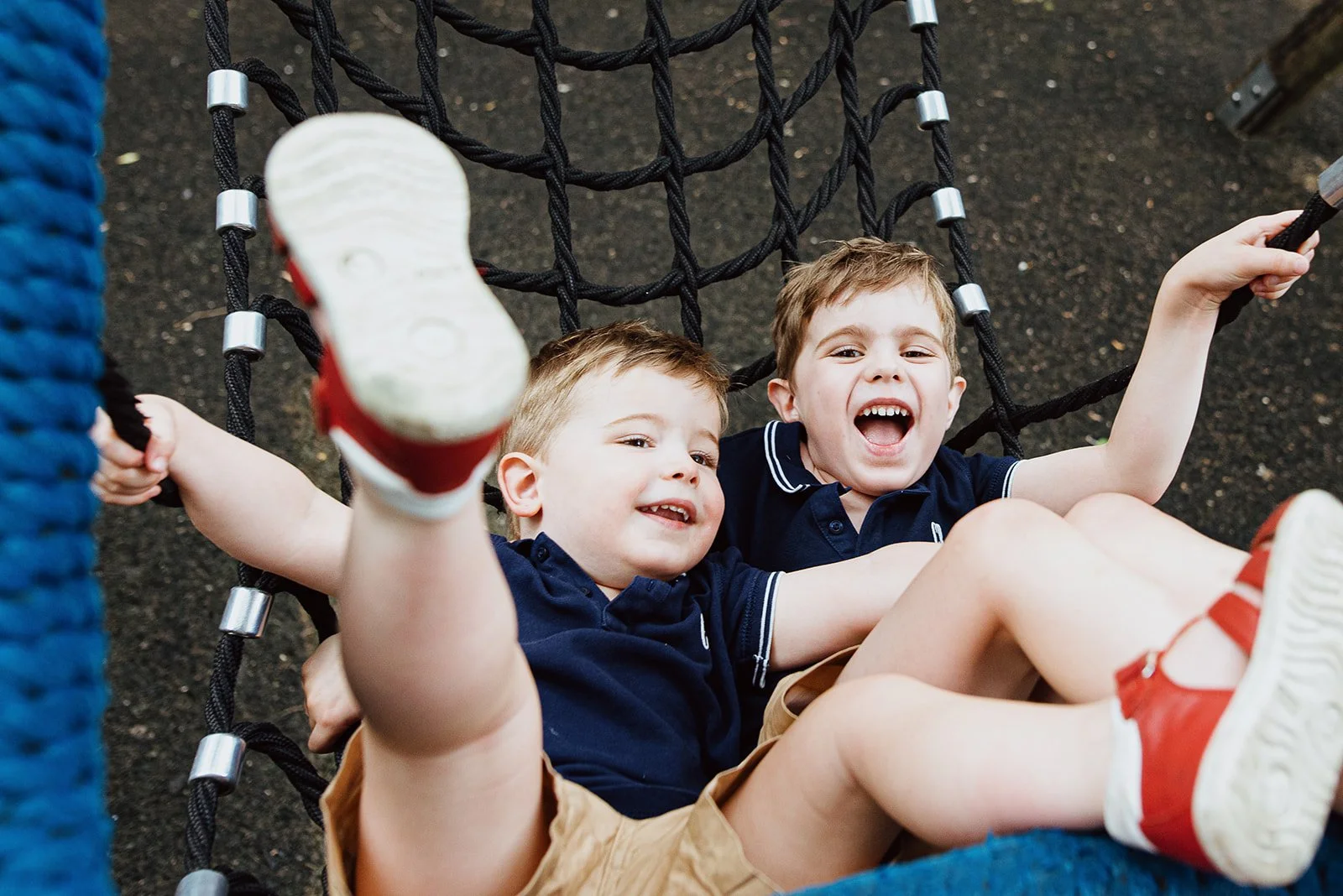 London family photographer captuirng boys in swing in playground in Clapham, South London. Award-winning lifestyle family photography.