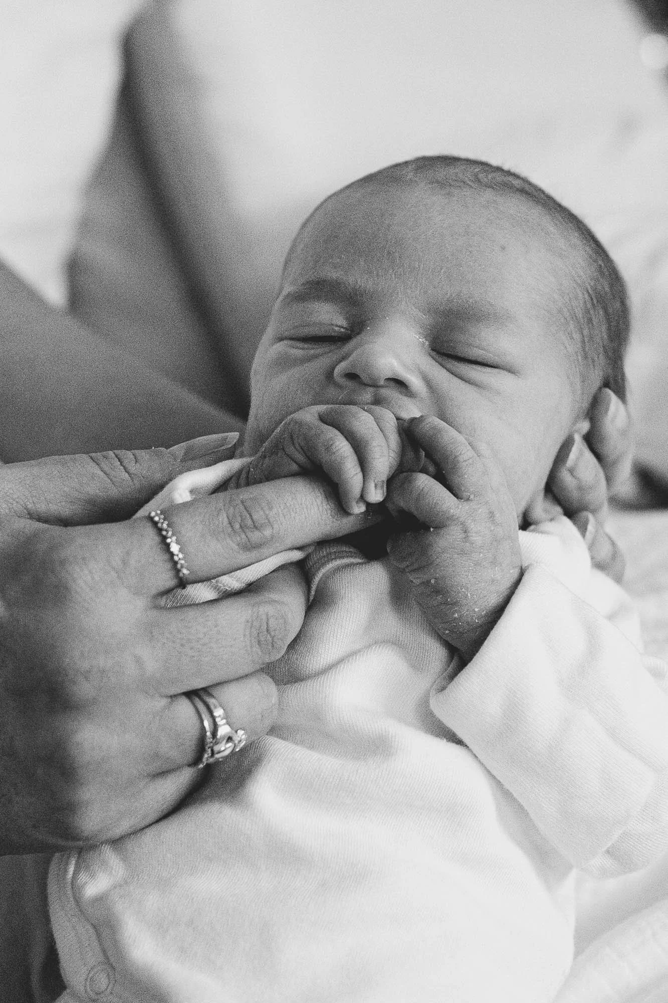Natural newborn portraits Chichester, baby boy holding mother's finger, black and white newborn baby photos by award-winning Chichester newborn photographer.