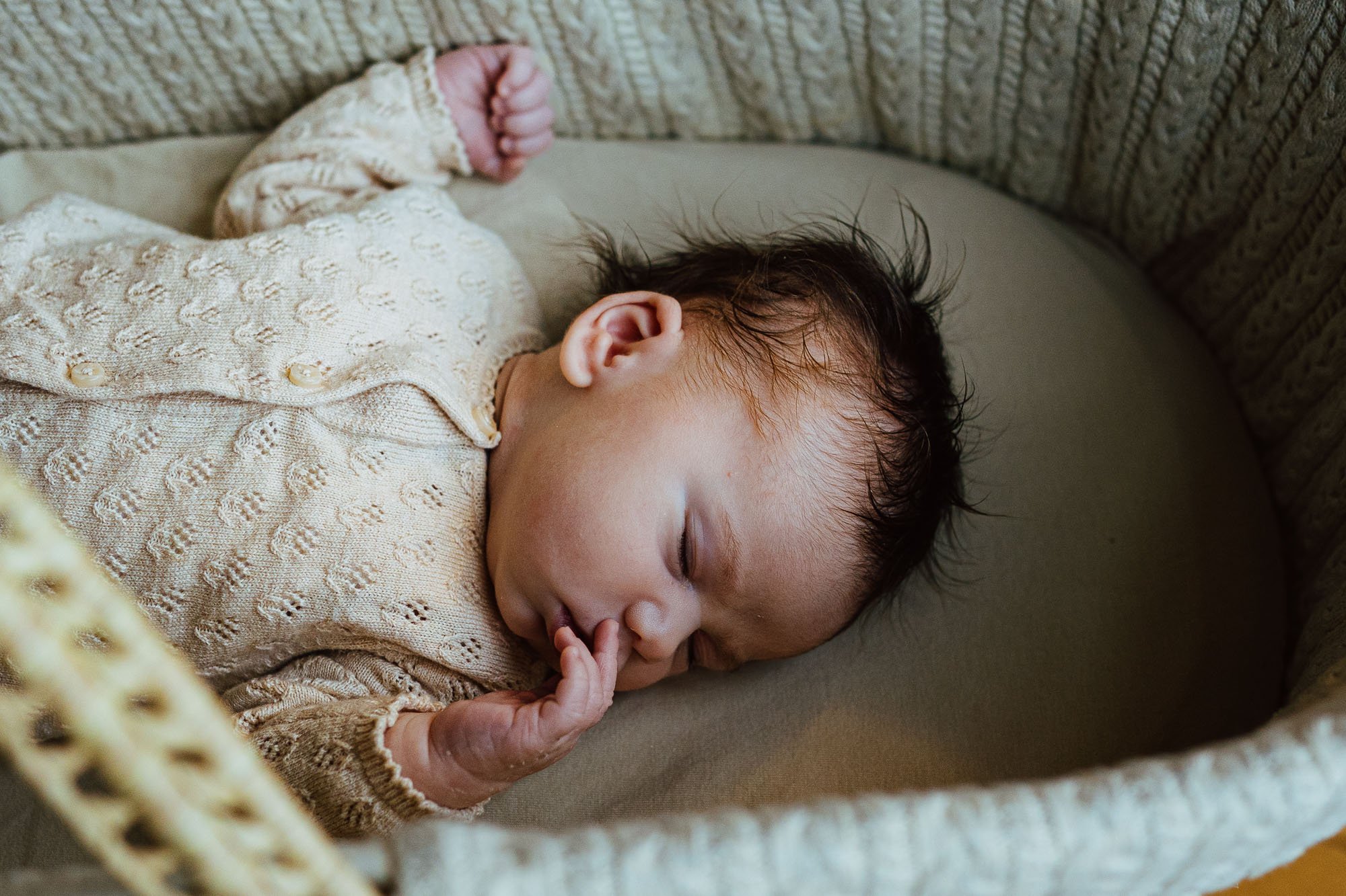 Baby girl asleep in moses basket, natural documentary-style newborn photography in Chichester and across West Sussex.