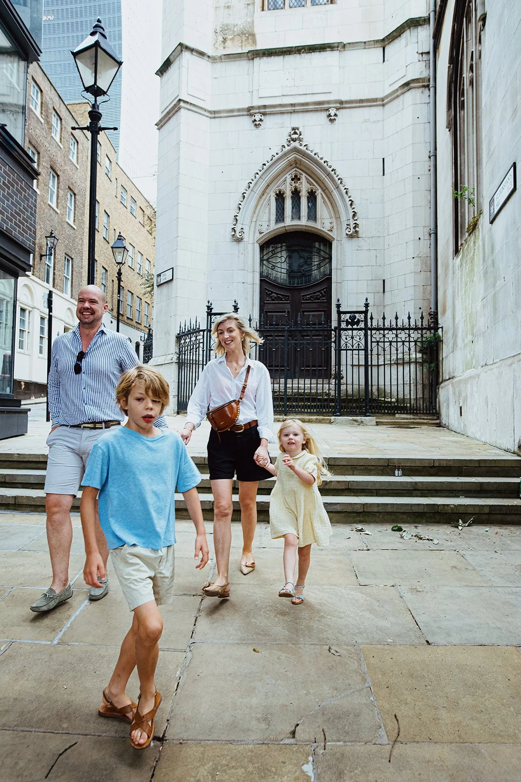 London family vacation shoot, parents and children walking from St Dunstan in the East Church Gardens towards the Tower Bridge during a reportage style unposed family photoshoot whilst on holiday.