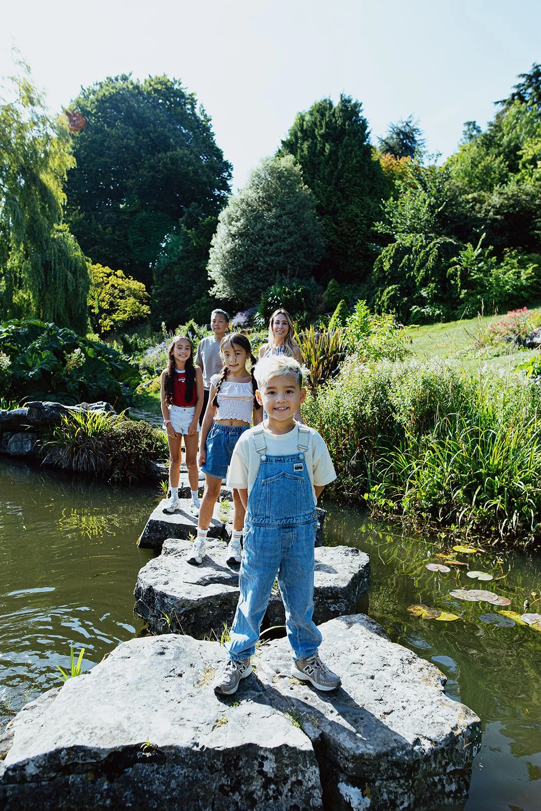 Family portrait taken at the Rocky Gardens in Preston park, children and parents posing on the stones in the water. Natural lifestyle family photography in Brighton & Hove.