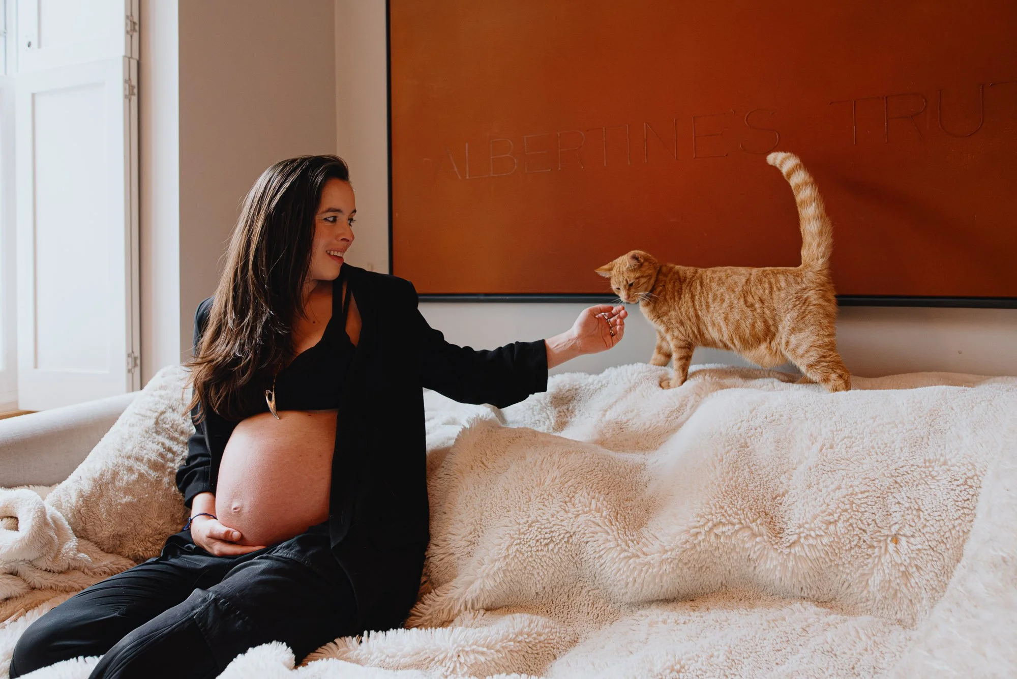 Hove maternity photography at home, pregnant woman with cat on sofa at home in Hove, East Sussex.