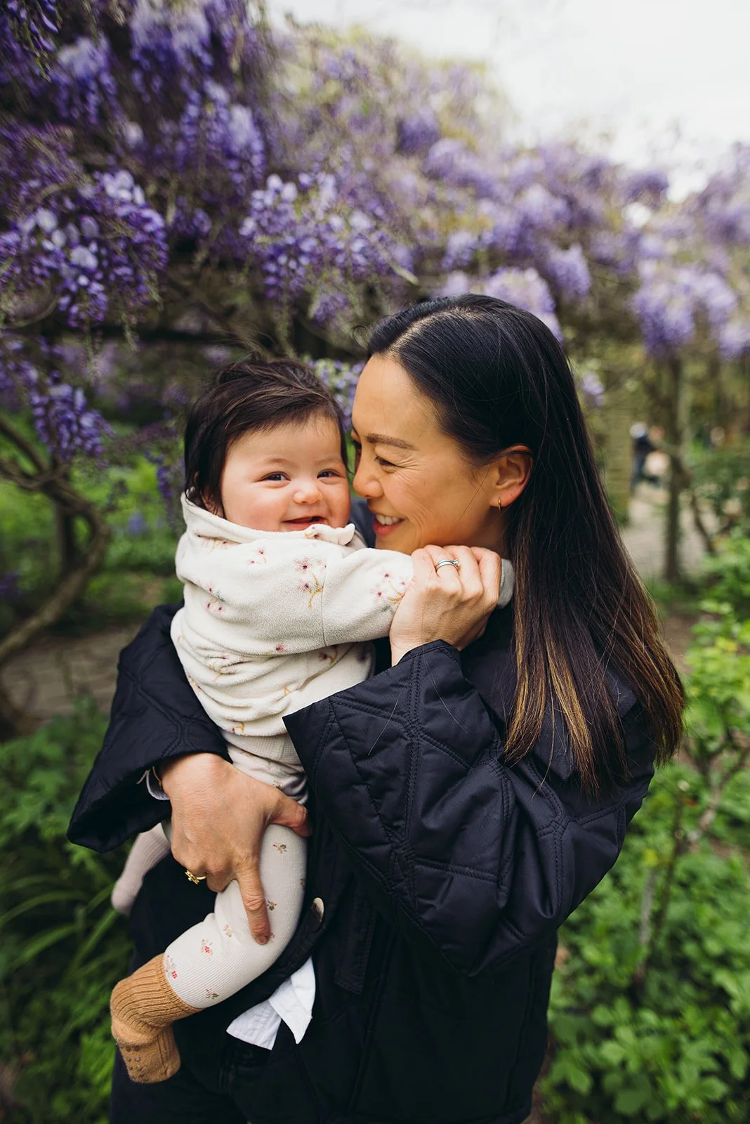 Mother and baby girl smiling during their family photoshoot on Hampstead Heath near their house in Finchley Road.