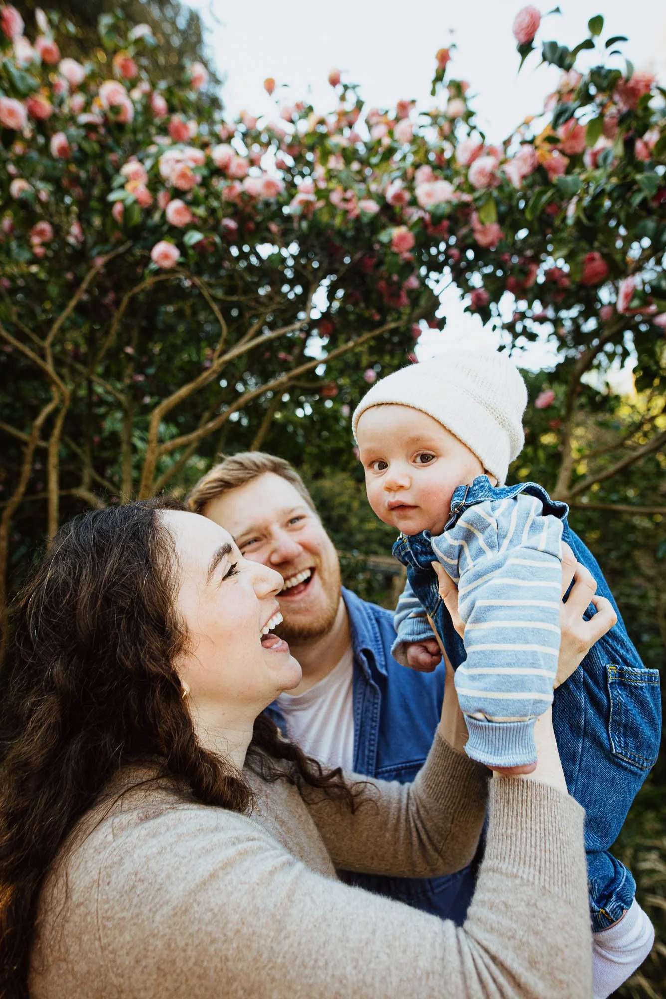 Family photoshoot Billinghurst, park, blossom in the background and smiling parents with baby boy.