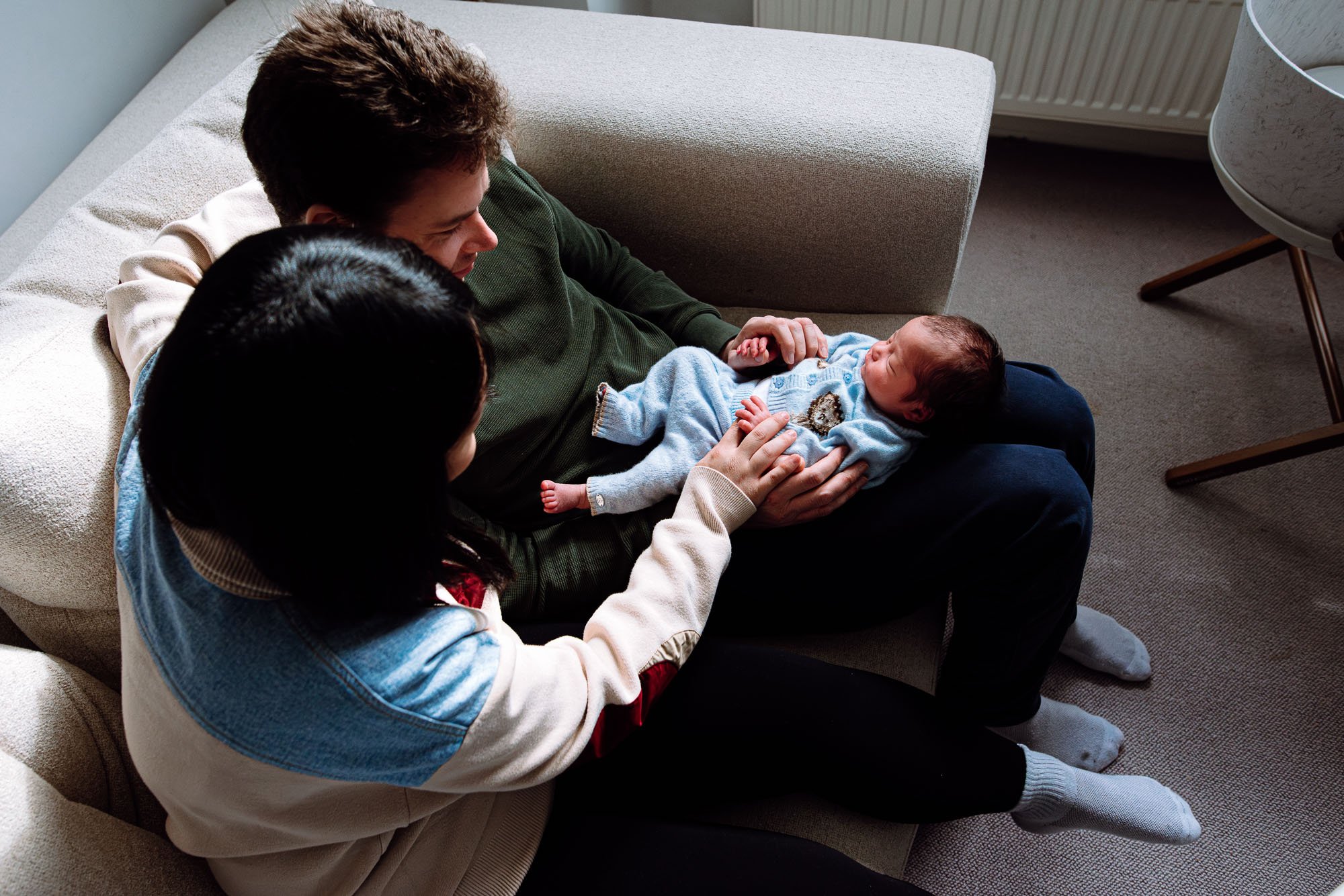 Newborn photoshoot Clapham, baby boy on father's lap, natural newborn session in Clapham and across South London. Award-winning baby photography.