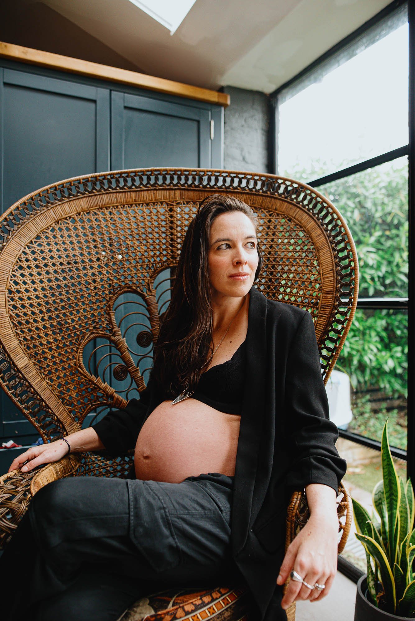 Award-winning maternity photography in Wimbledon and across South London. Portrait of pregnant woman looking out of the window at home.