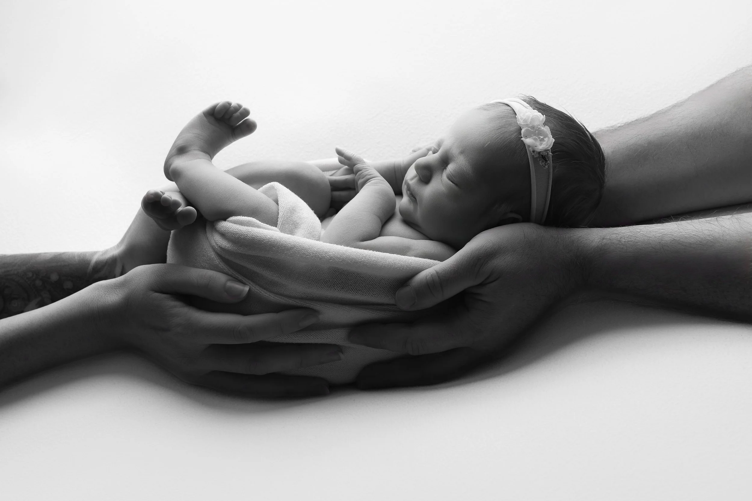 Held in the parents hands showing just how tiny baby really is at this stage. It will be beautiful to look back on as they grow