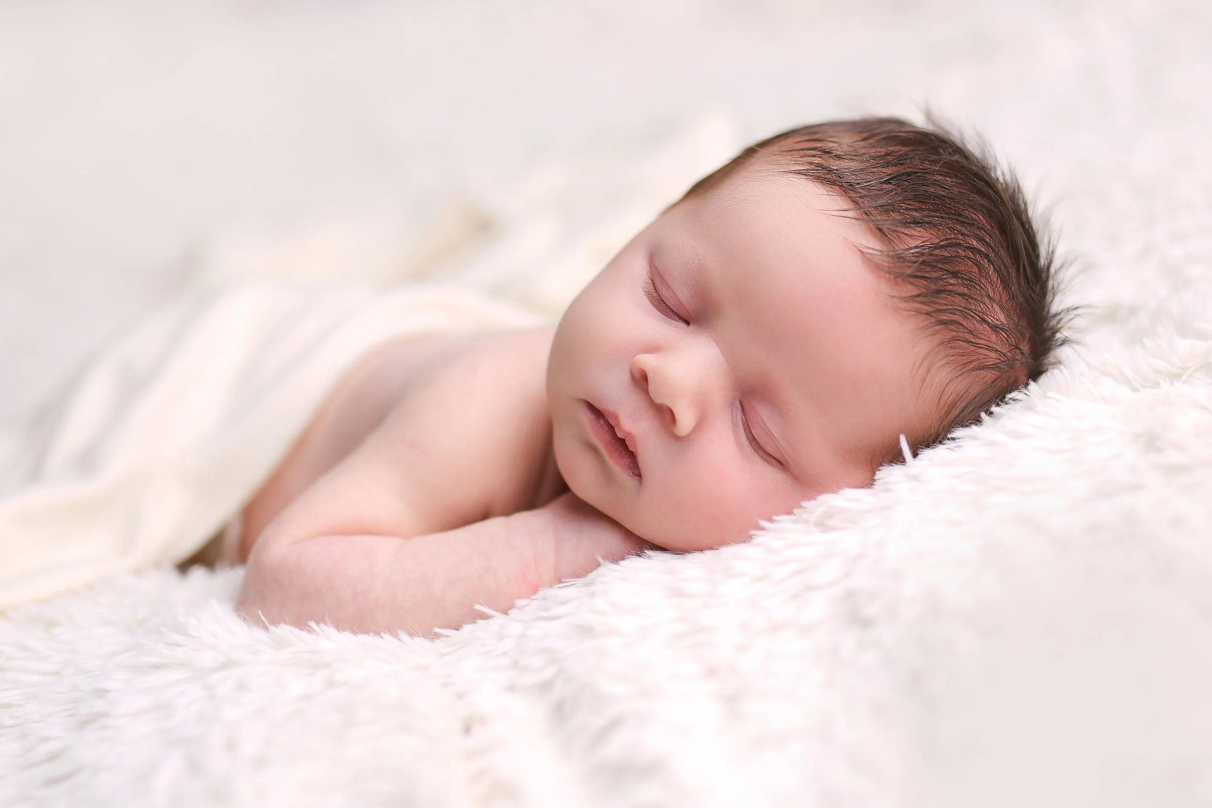 Naturally posed newborn sleeping in their photoshoot, with lots of hair