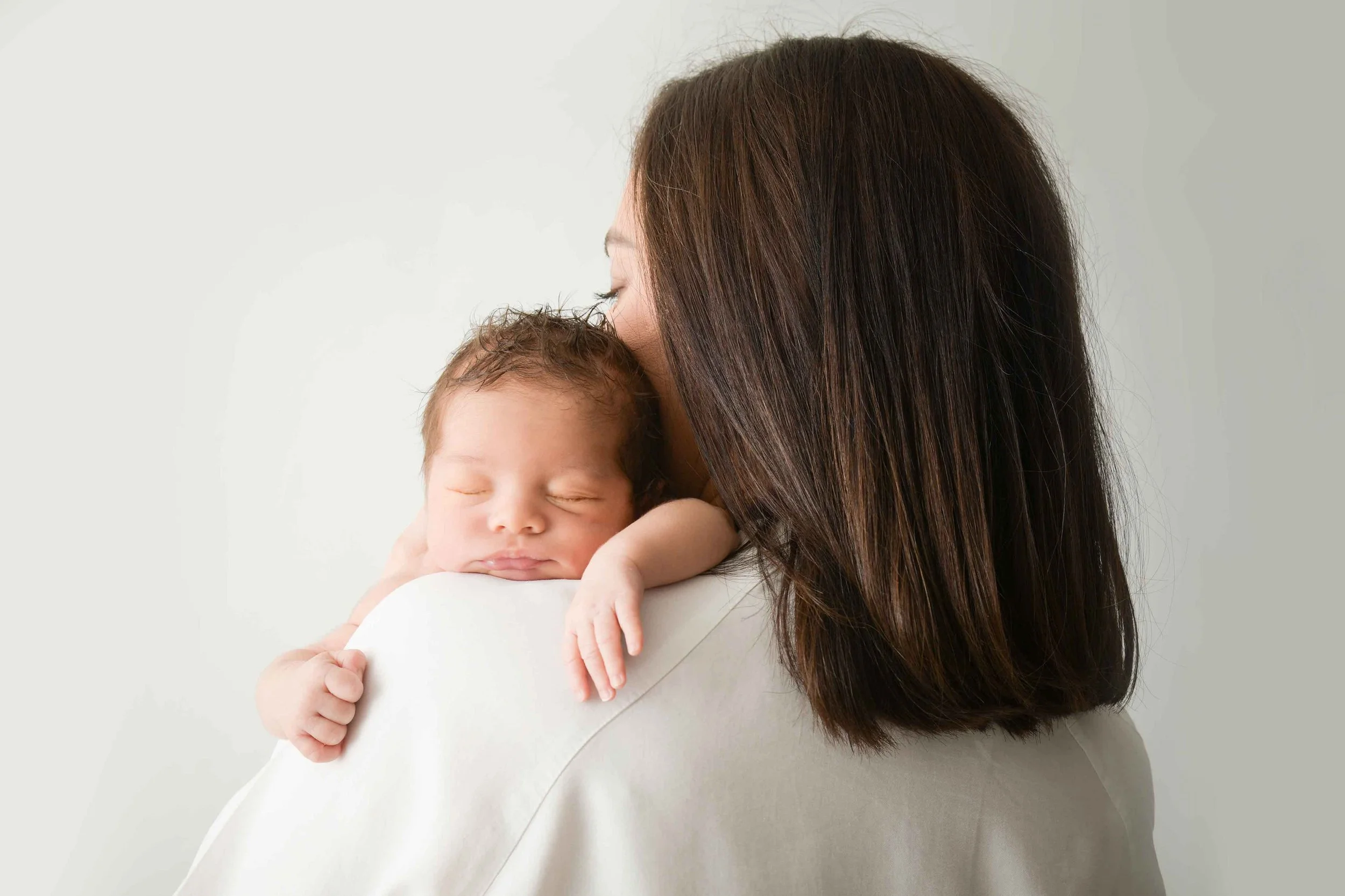 Baby comfortably sleeps on parents shoulder. 