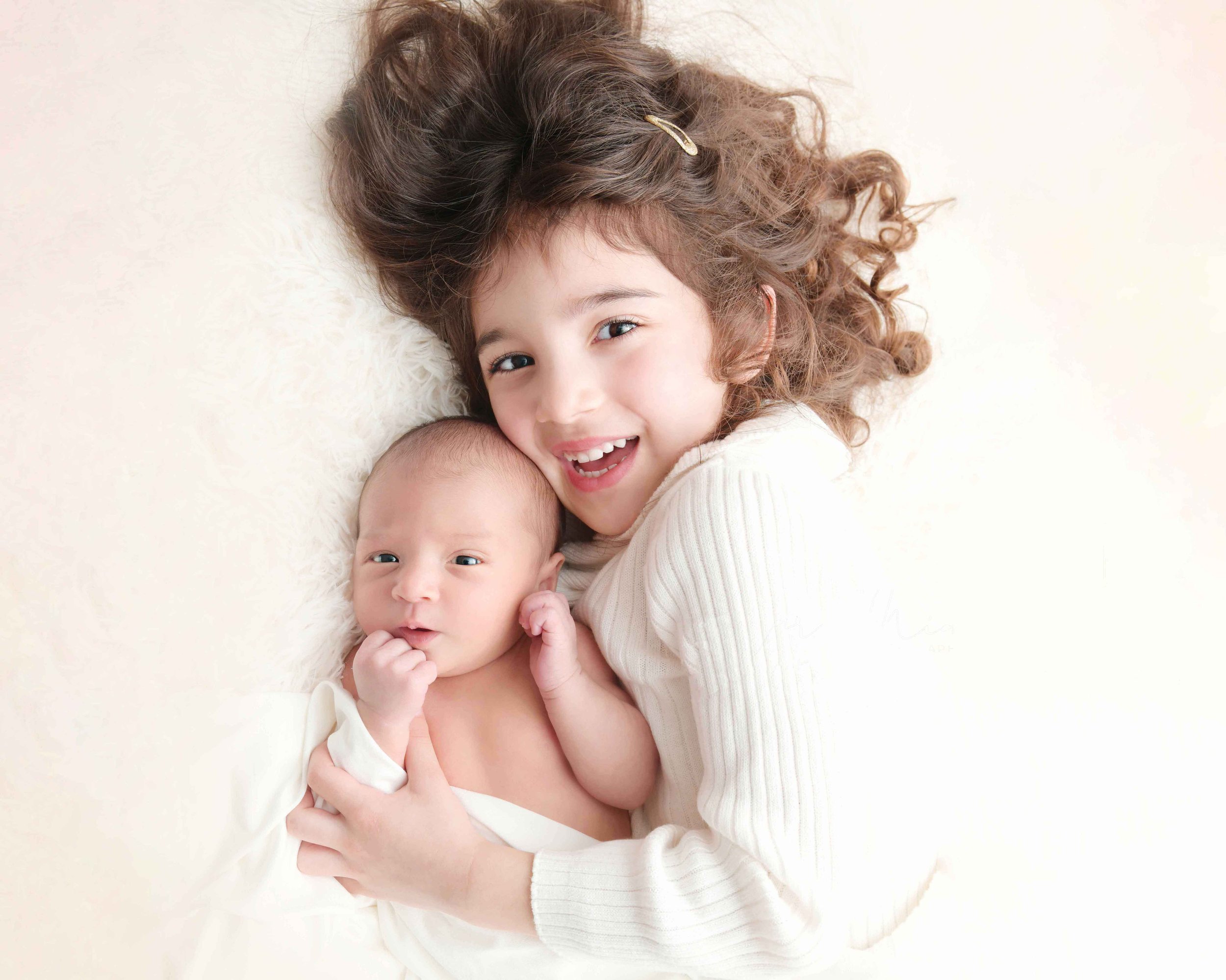 Newborn is wide awake with their sibling in the photo studio