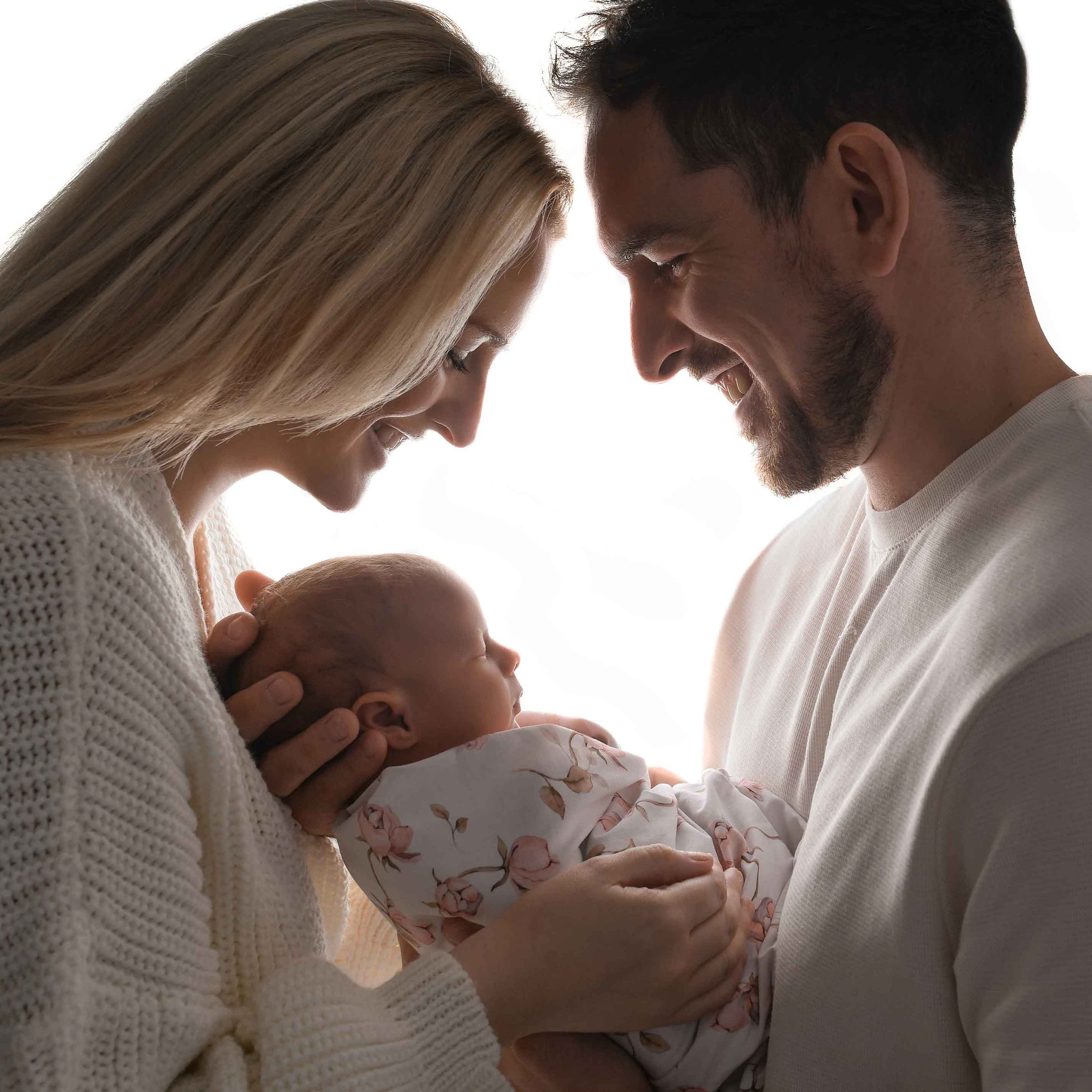 Newborn held by parents in emotionally back lit image in the photo studio 