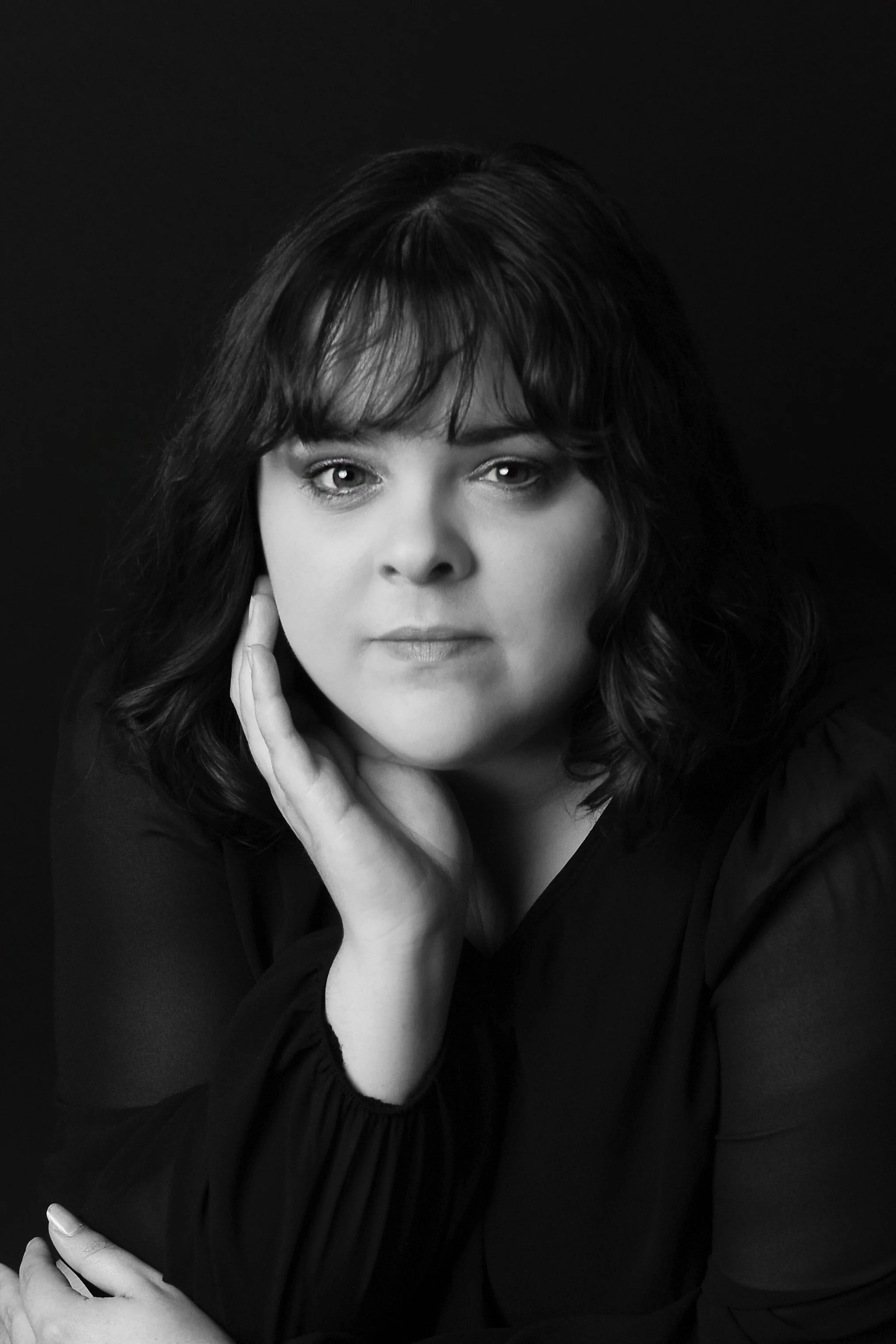 Black and white headshot portrait of the studio photographer on a black background. Studio perfect for formal headshots