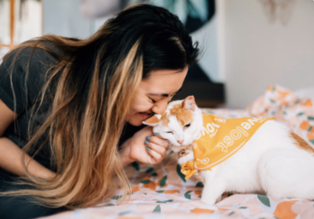A woman snuggles her orange and white kitty.