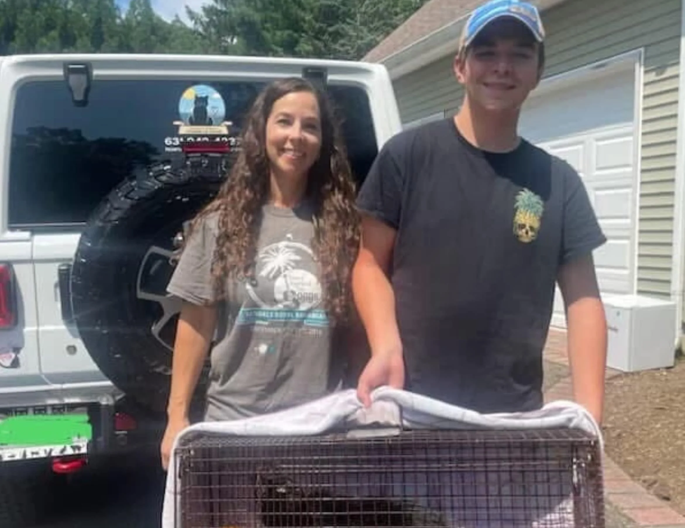 Two teenage volunteers helping transport a kitten in a carrier for care.