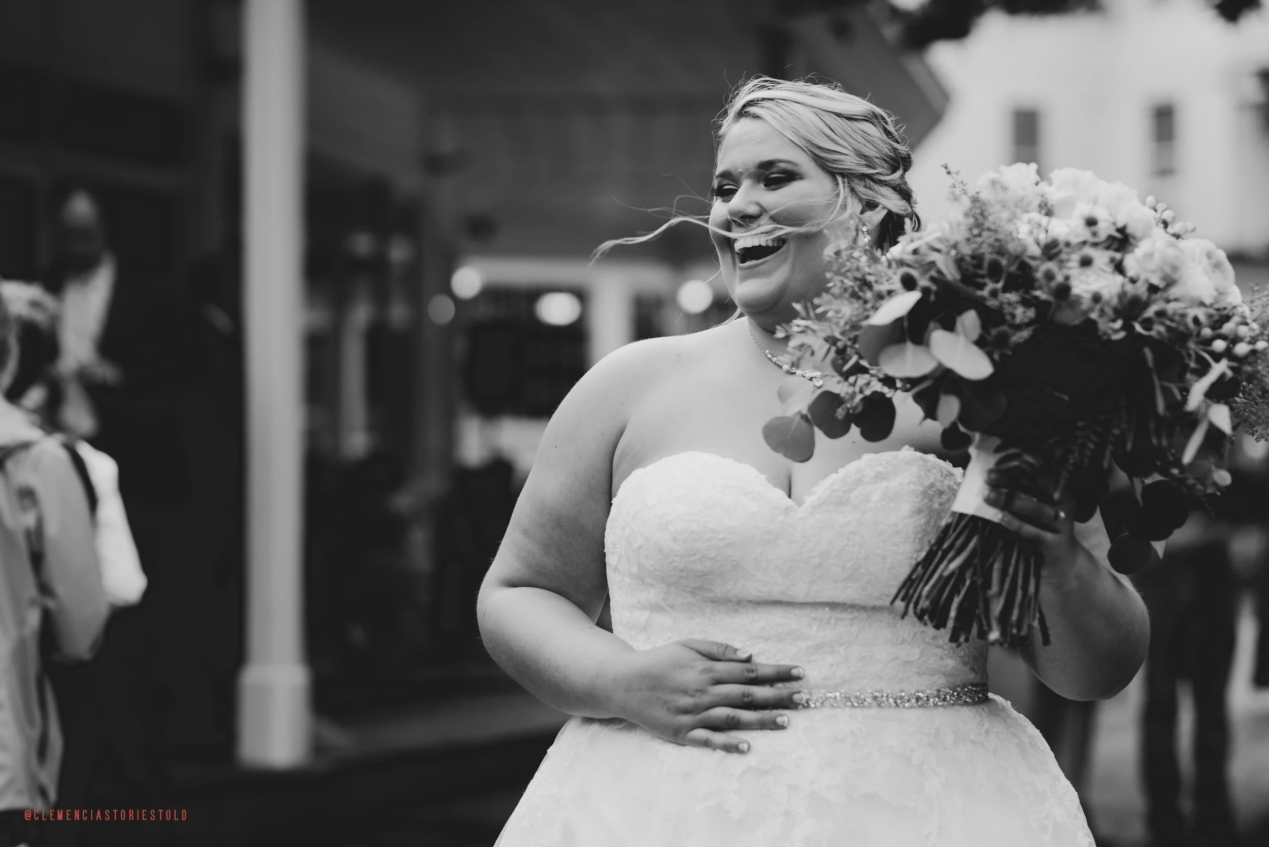 A smiling bride in a strapless wedding gown holding a large bouquet of flowers.