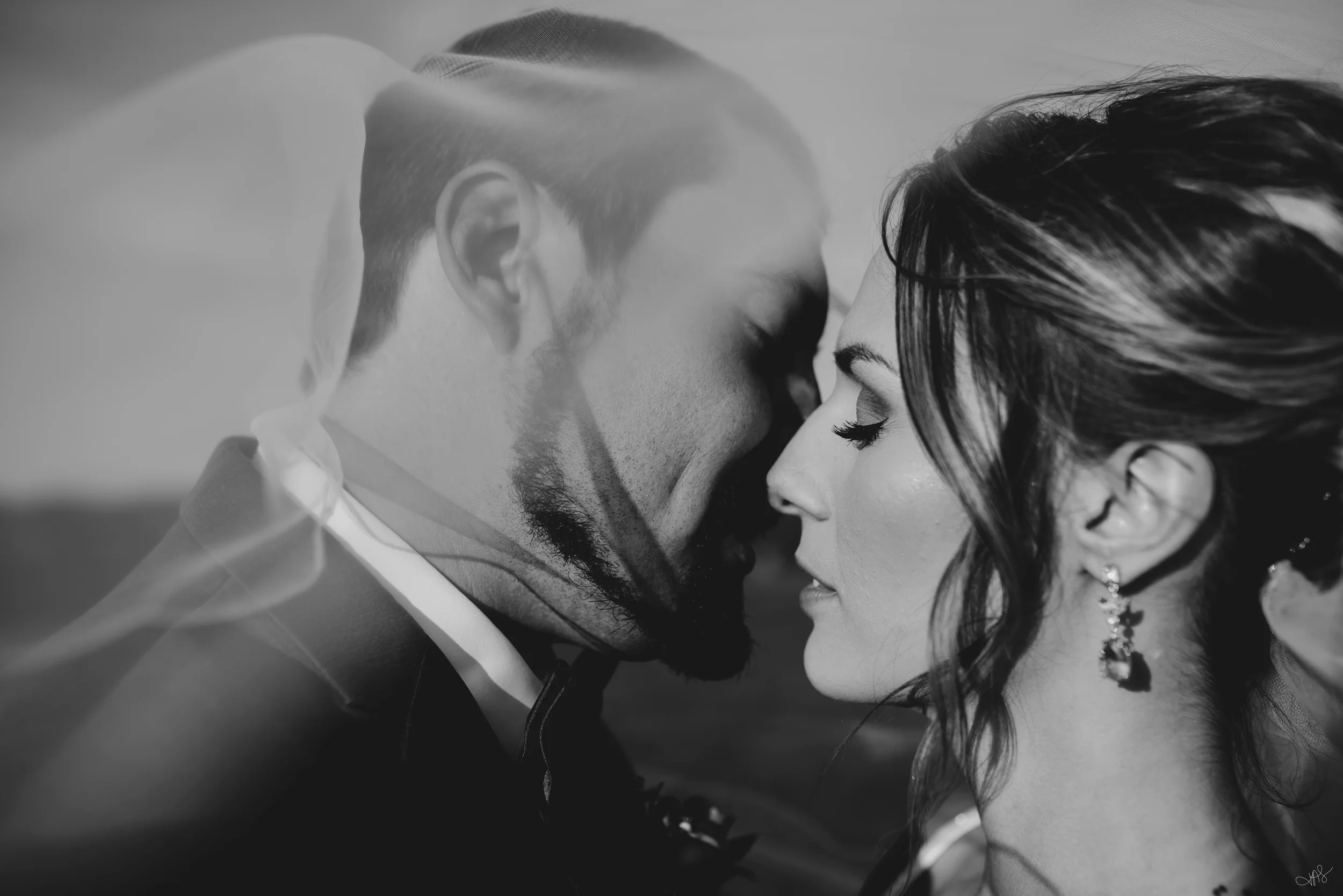 A black and white close-up photograph of a couple with their foreheads touching, eyes closed, appearing to share an intimate moment.